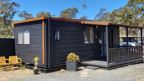 Black cabin 92 with a porch, outdoor seating, and plants at Stawell Grampians Gate Hotel Motel