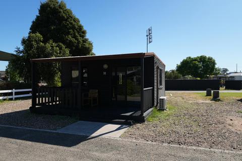 Black cabin at Stawell Grampians Gate Hotel Motel with a shaded porch and a outdoor seating