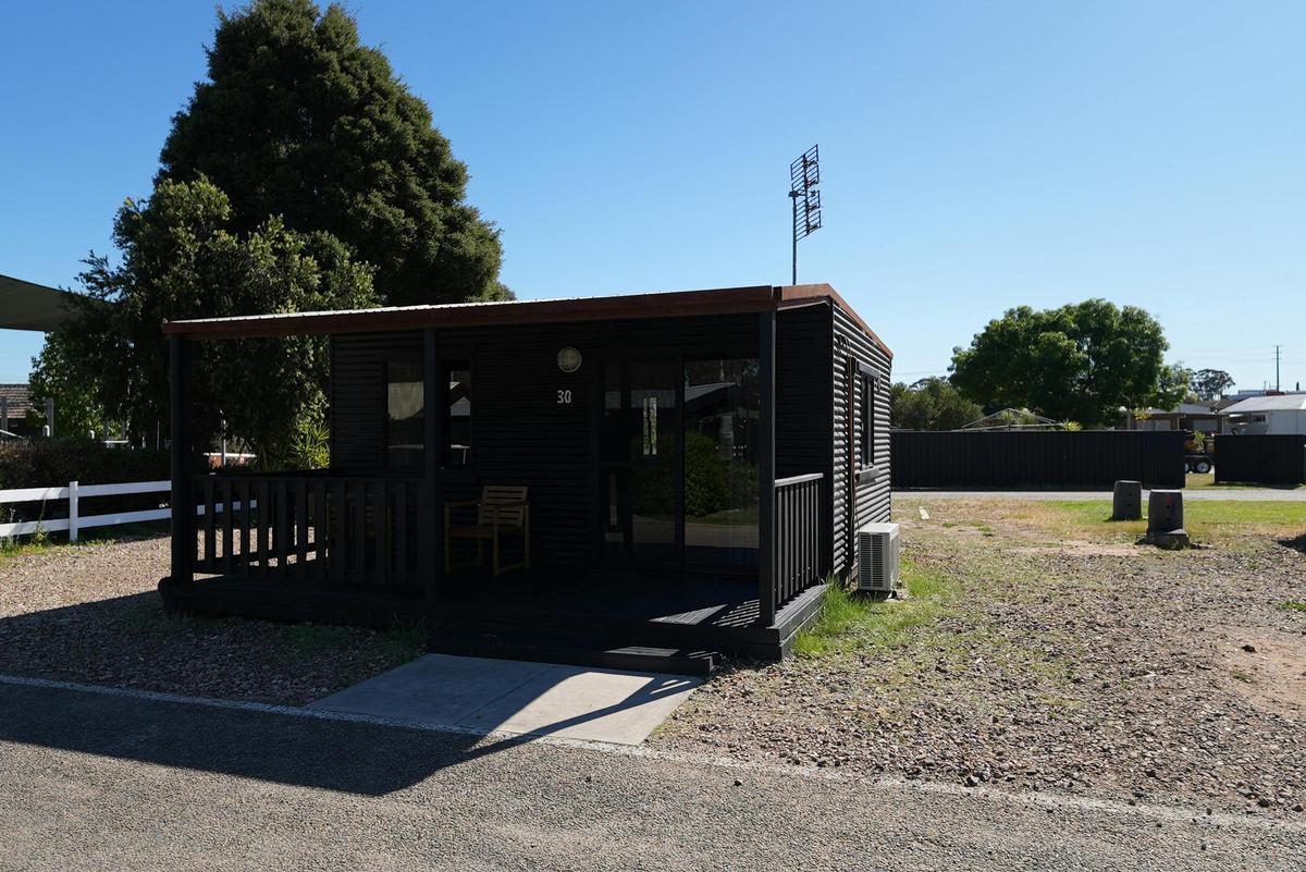 Black cabin at Stawell Grampians Gate Hotel Motel with a shaded porch and a outdoor seating