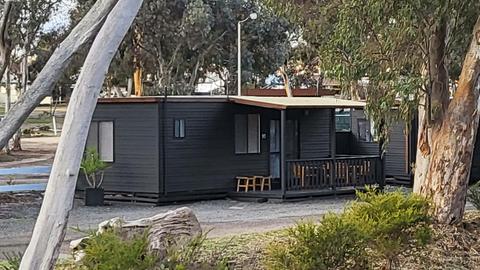 Black cabin 91 with a porch and surrounded by natural greenery at Stawell Grampians Gate Hotel Motel