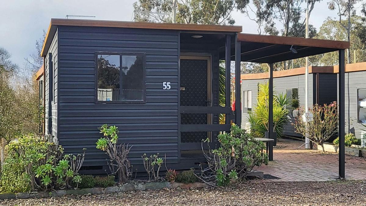 Black cabin 55 with a covered patio and garden plants at Stawell Grampians Gate Hotel Motel