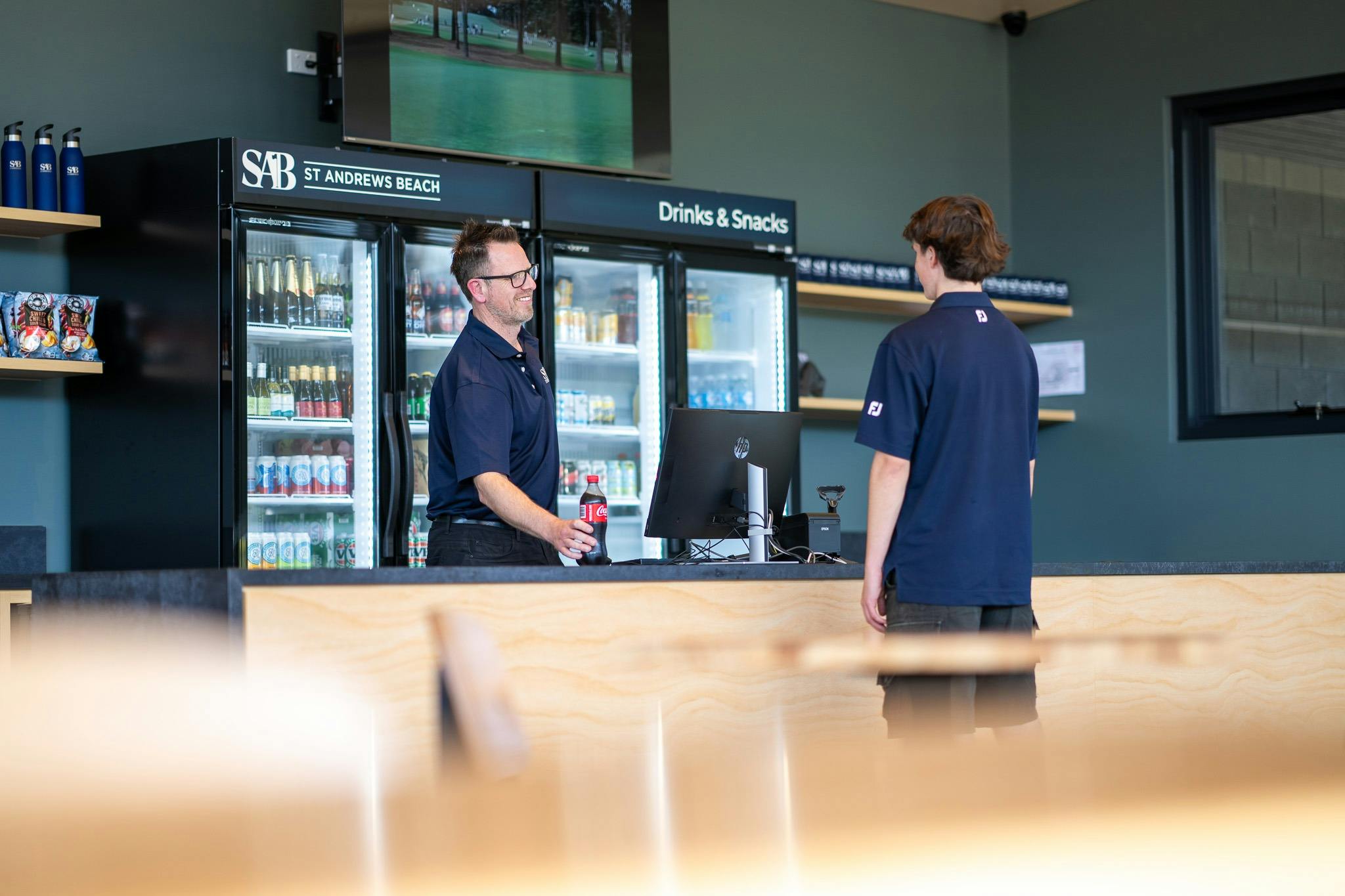 A staff member of St Andrews Beach Golf Course serving a customer a drink