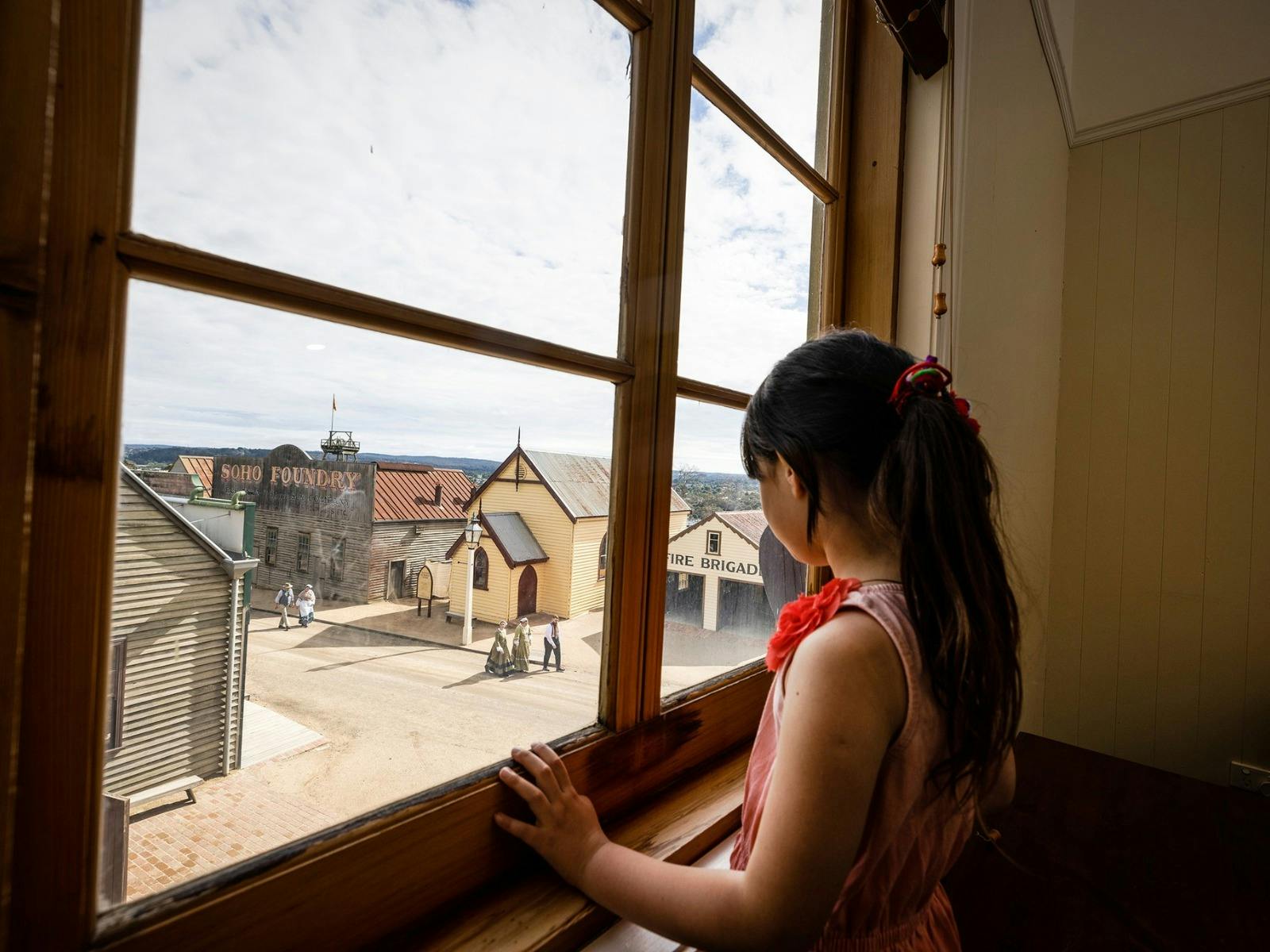 Girl looking outside window with view over Sovereign Hill Main Street