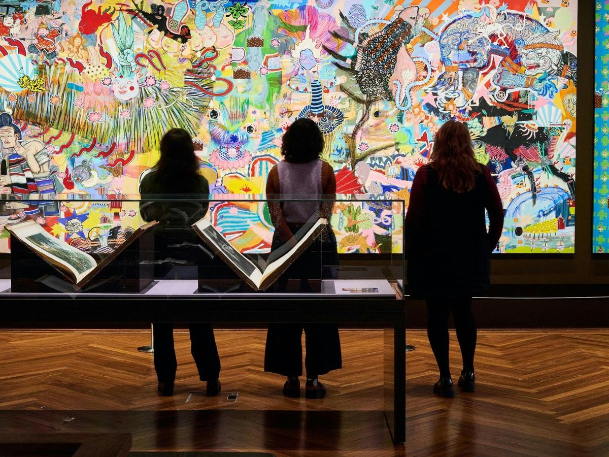 Three people looking at artwork in State Library Victoria