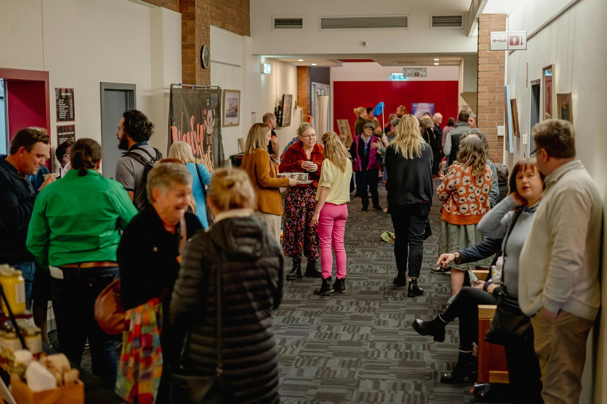 The foyer is being utilsed during an event - there are people spread out down a narrow hall