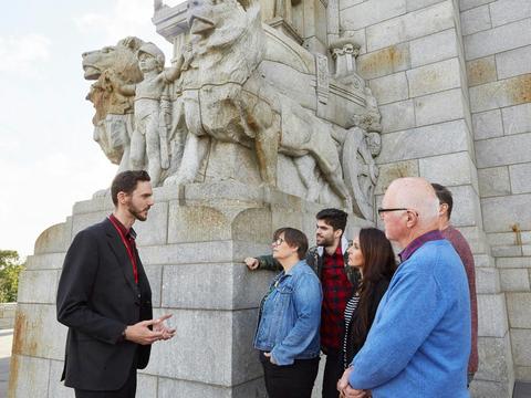 Tour Guide with  tour participants standing beside the Shrine of Remembrance