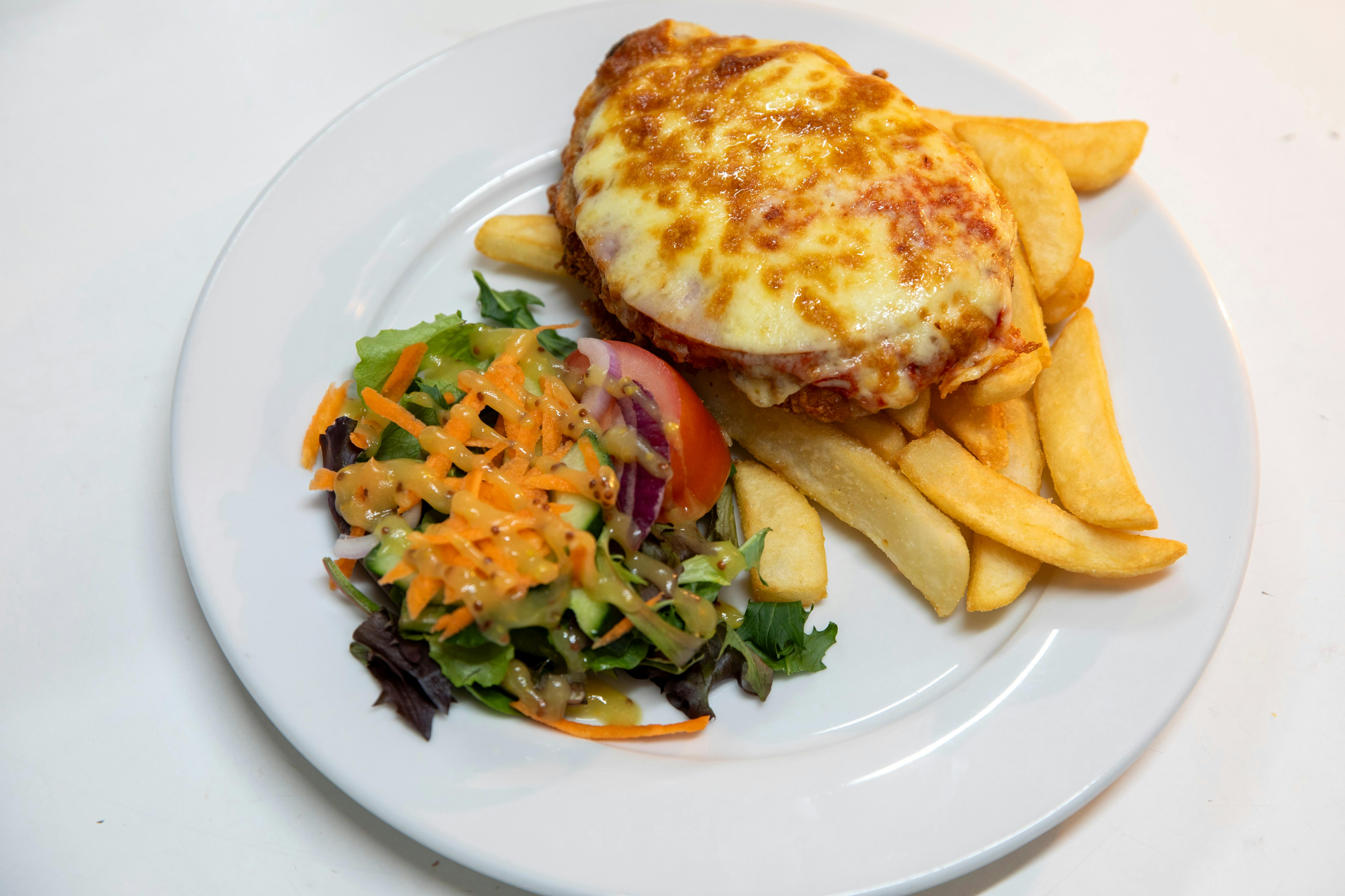 A parmigiana and salad on a white plate on a table