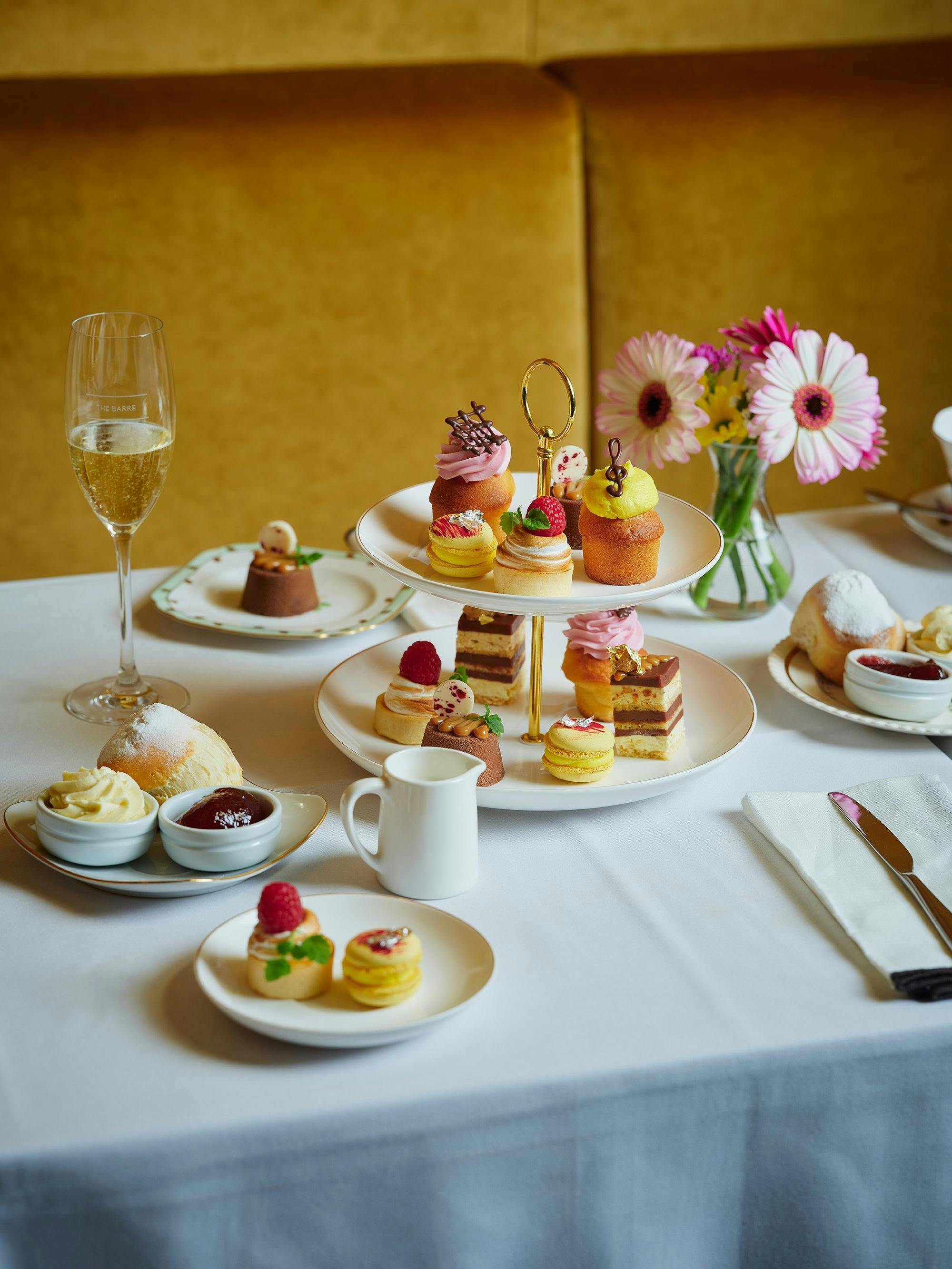 high tea set up on a table with food on high tea trays and a glass of sparkling wine