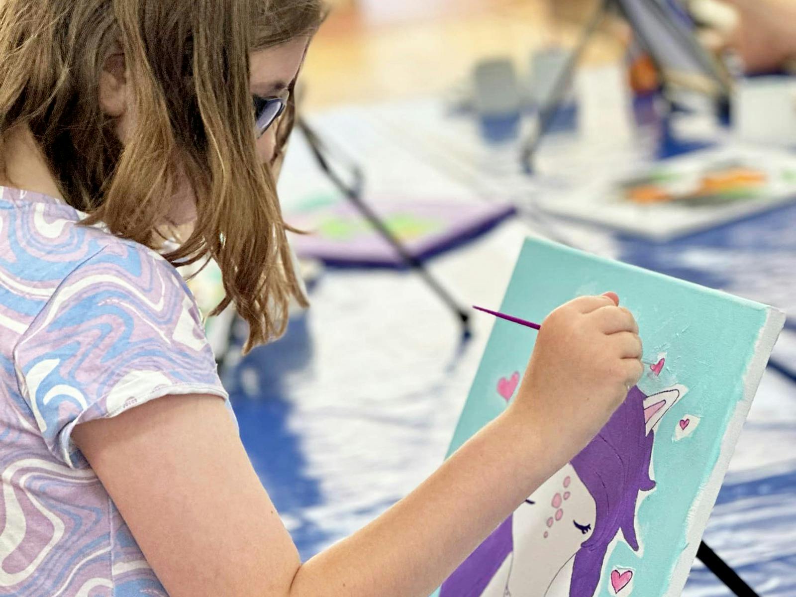 Child painting a canvas at The Art Club Hub