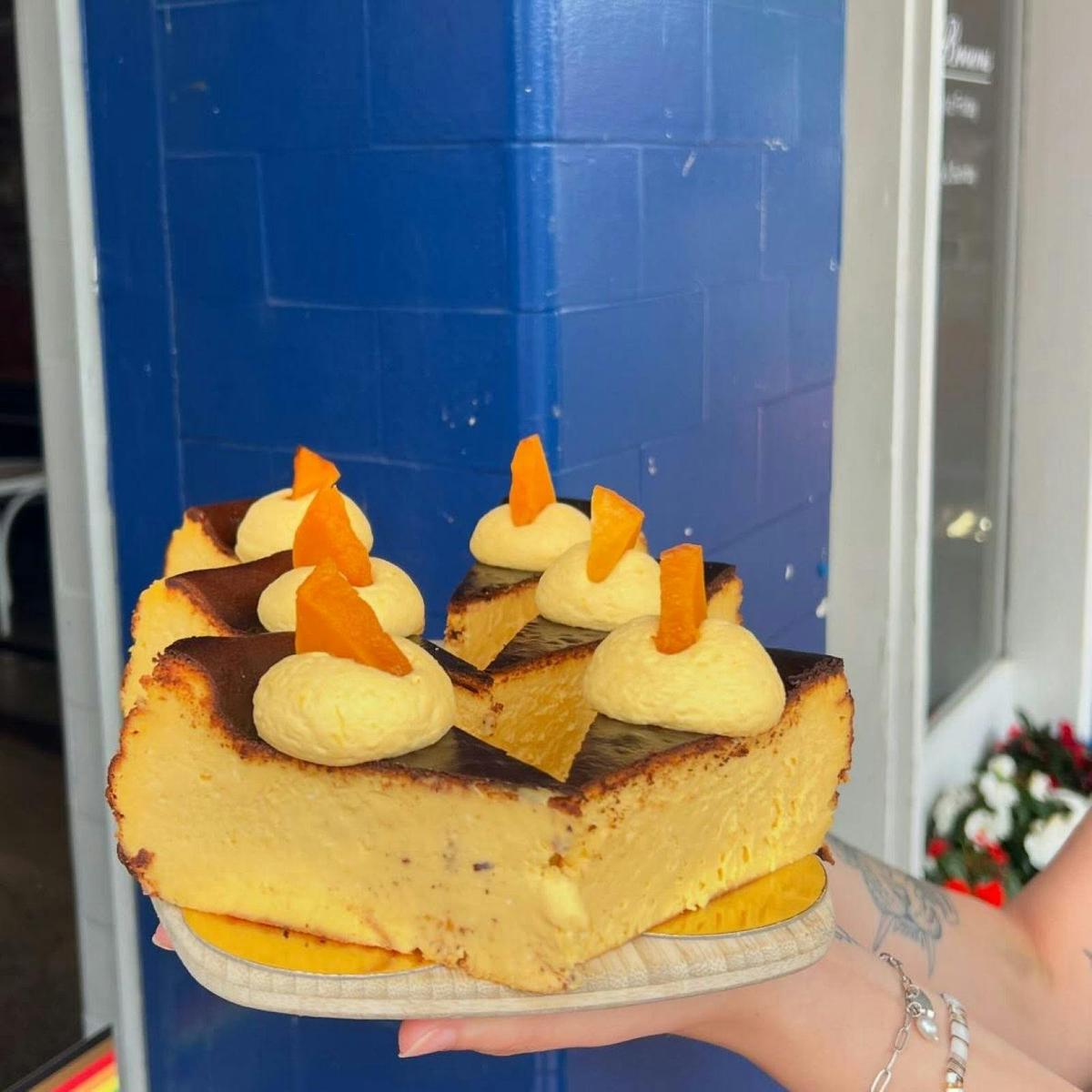A plate of slices of baked cheesecake against a blue wall.