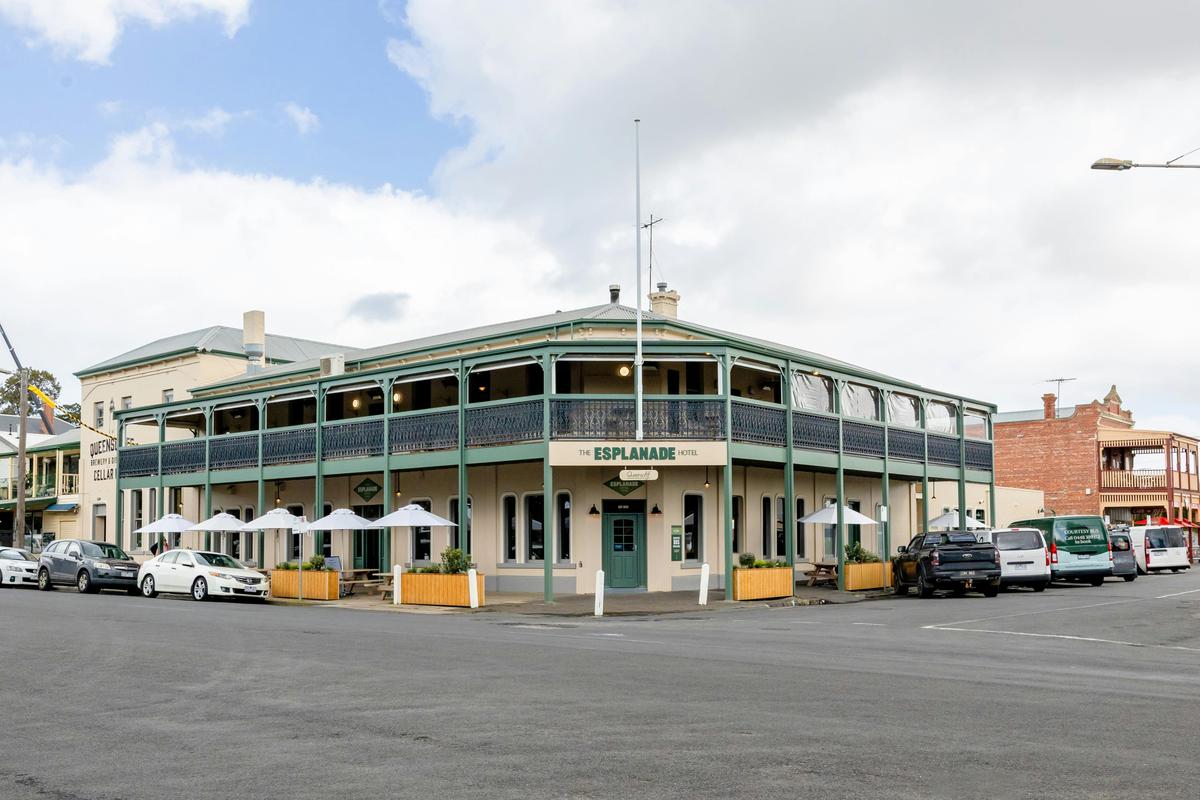 outside of building, cream and green building with umbrellas and tables outisde on the edge
