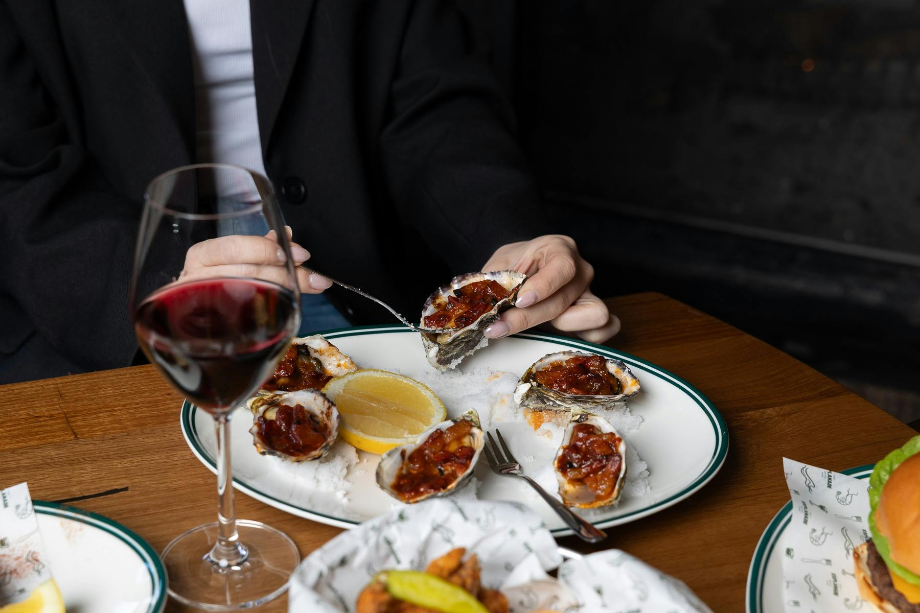 glass of red wine, oysters being eaten with a fork