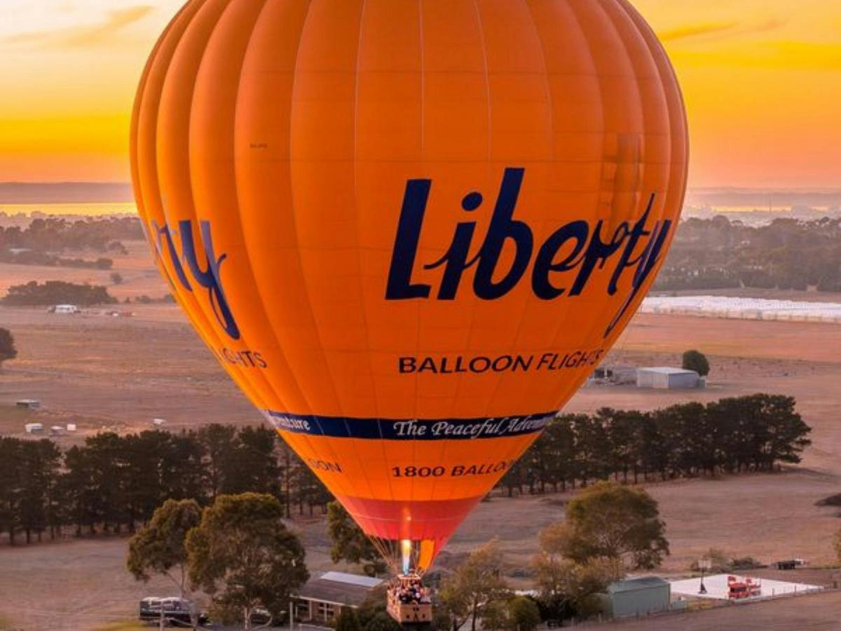Aerial view of a balloon drifting through the sky during a breathtaking orange sunrise