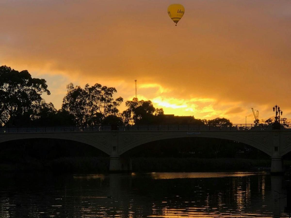 Hot air balloon floating over Geelong with a clear reflection in the river below