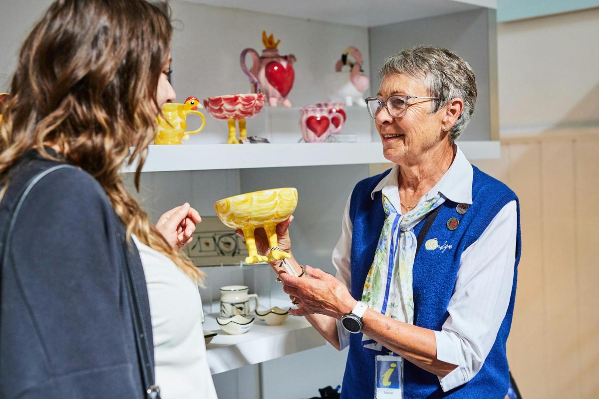 Volunteer showing a visitor a handcrafted pottery piece