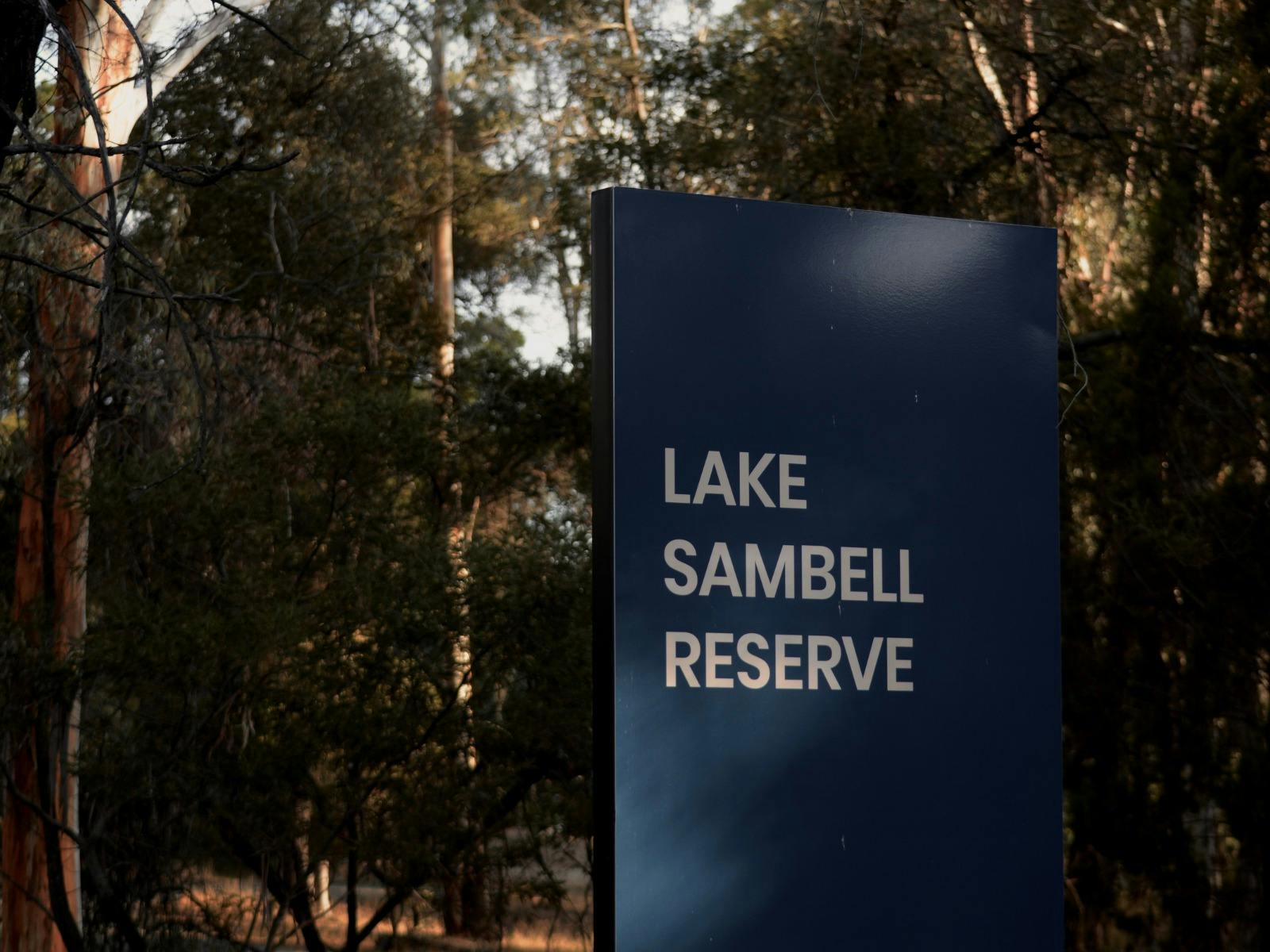 Lake Sambell Reserve sign surrounded by native Australian bushland, marking the entrance