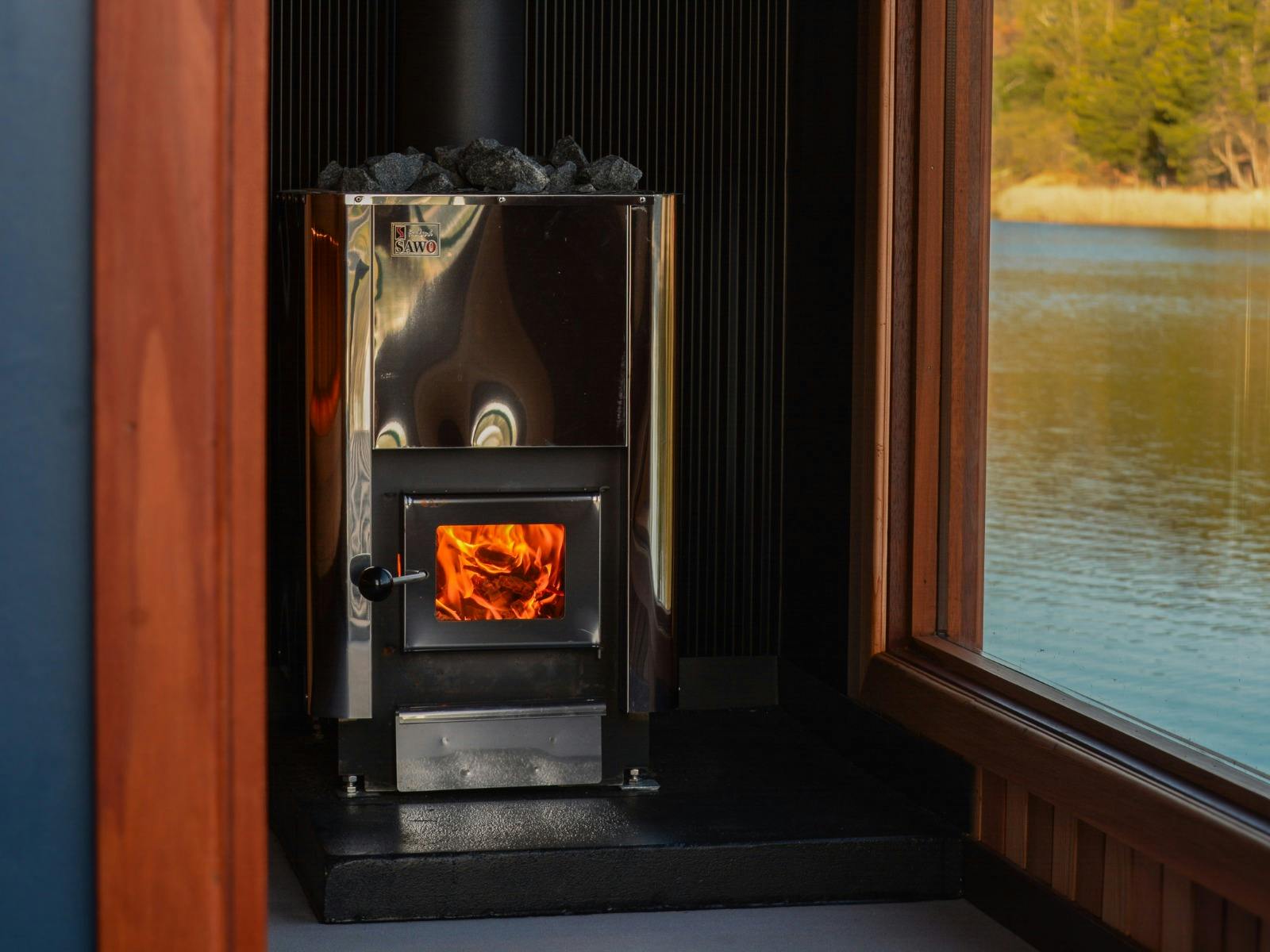 Close-up of the wood-fired sauna heater inside Stillwater Saunas, with warm flames glowing.