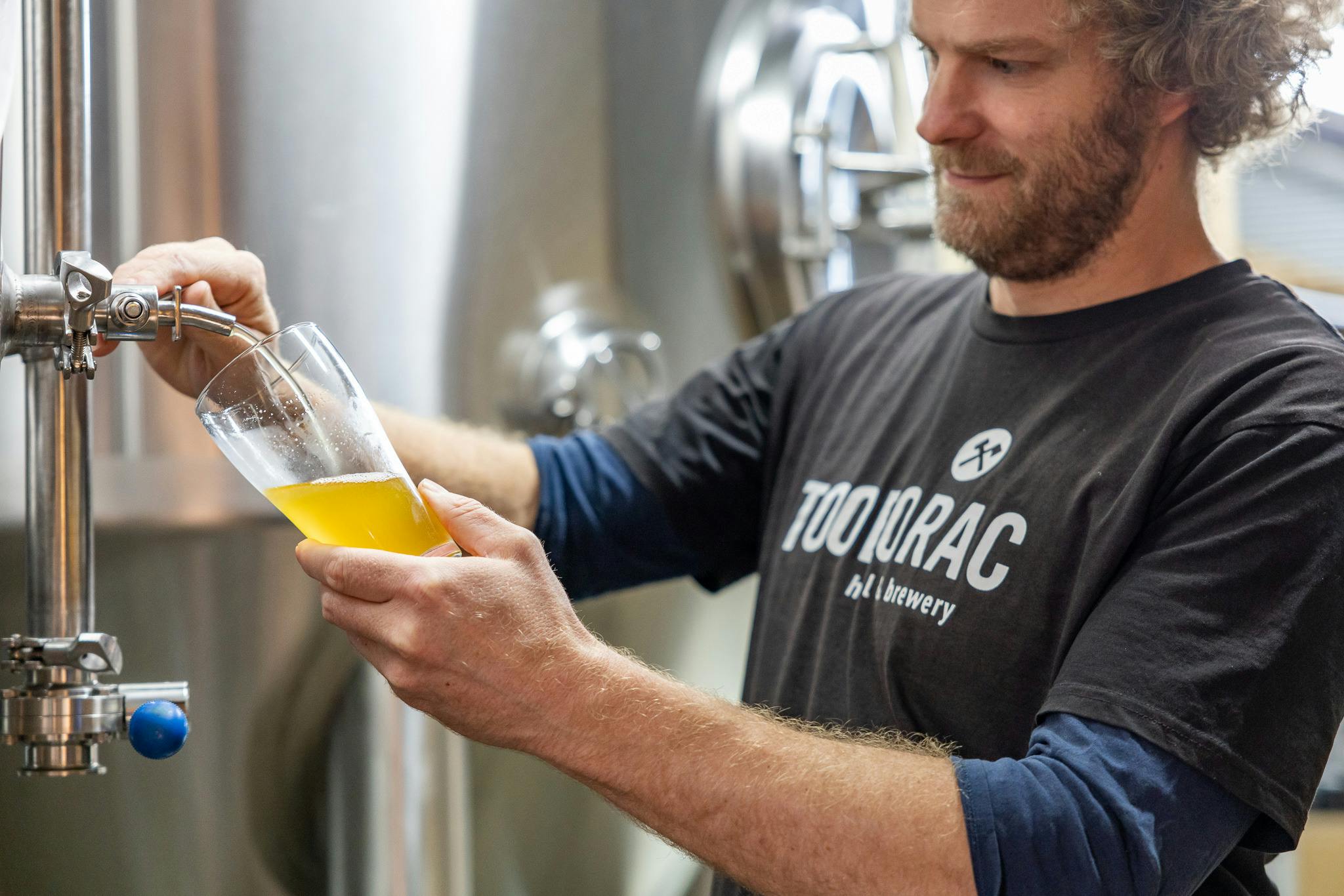 a person pouring a beer in a glass from a tap