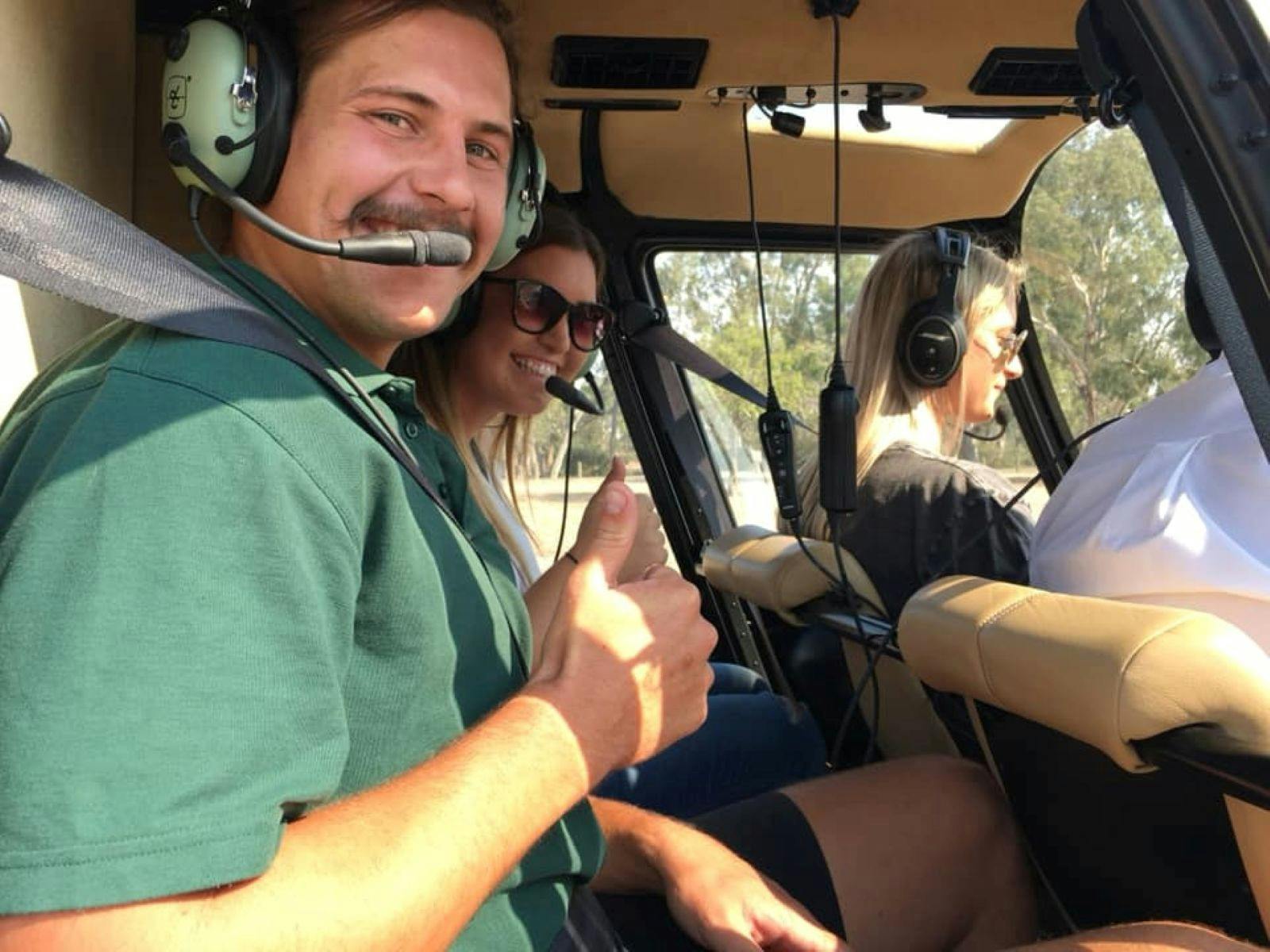 Three people in a helicopter looking at the camera