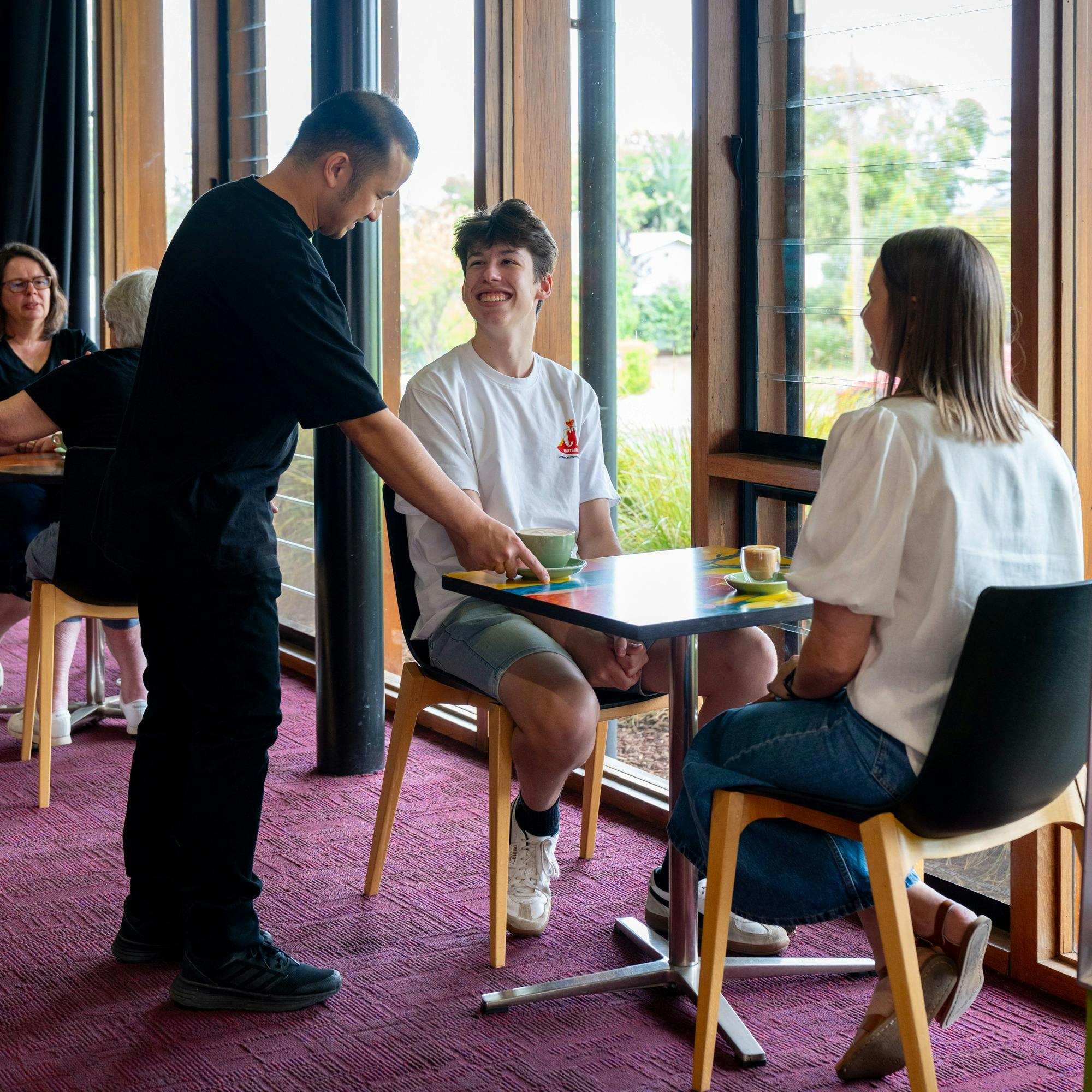 A server delivers coffee to two guests at the cafe overlooking the Sculpture Park