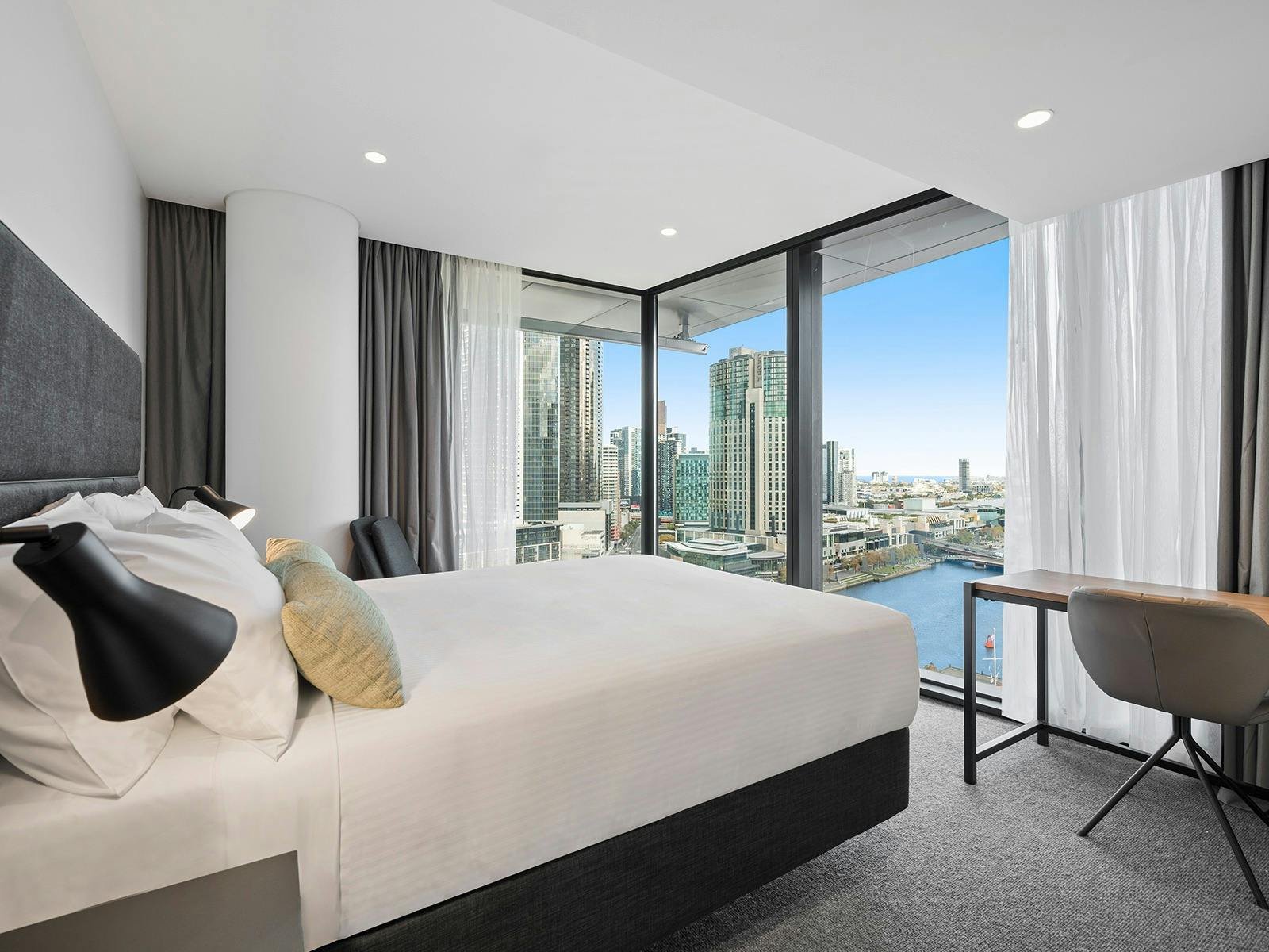 hotel room overlooking the city with a desk and chair in the right hand corner