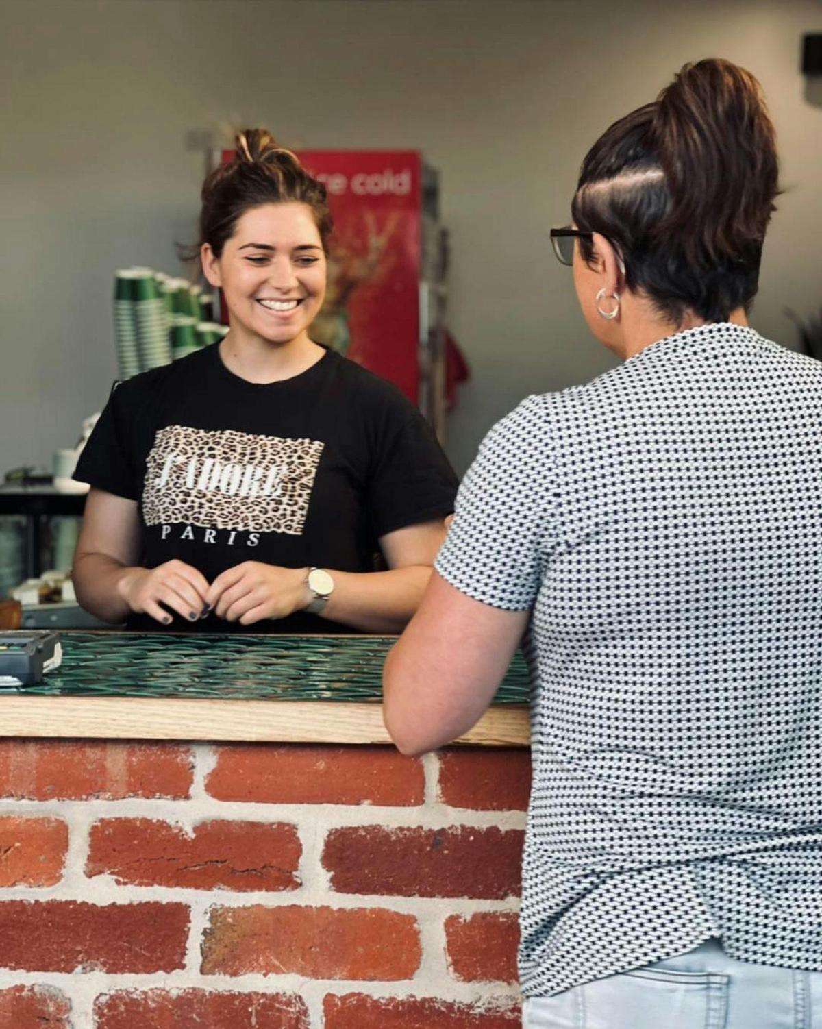 Serving staff smiling at customer over a counter