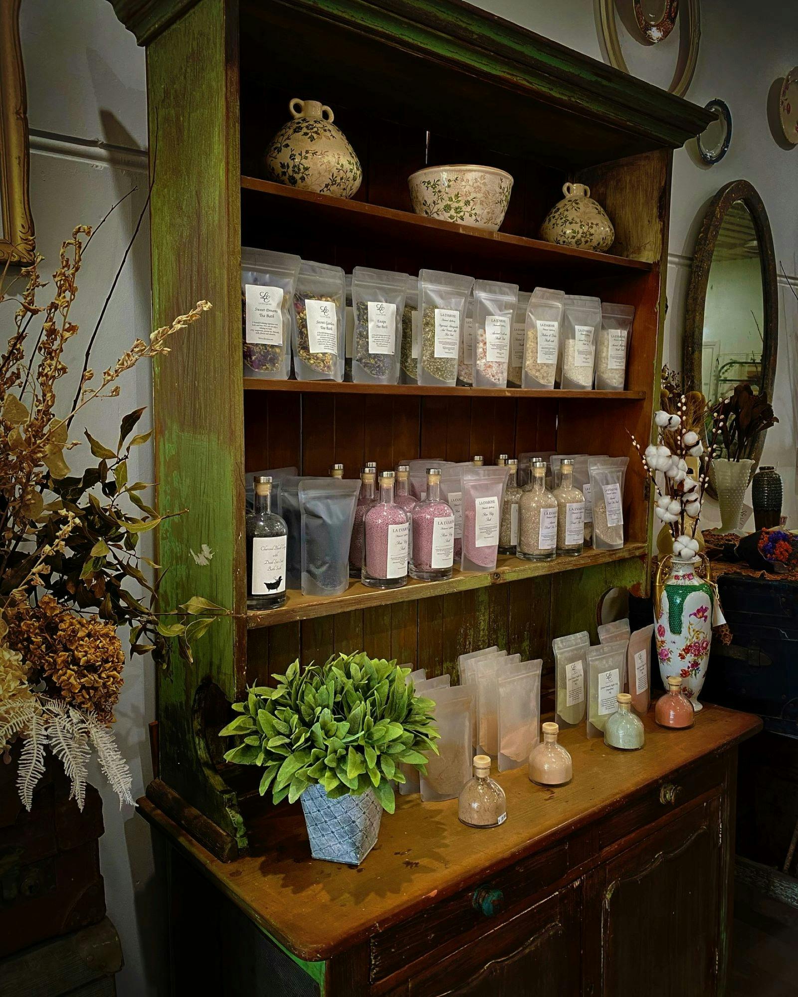 Different coloured bath salts in bags sitting in a wooden cupboard
