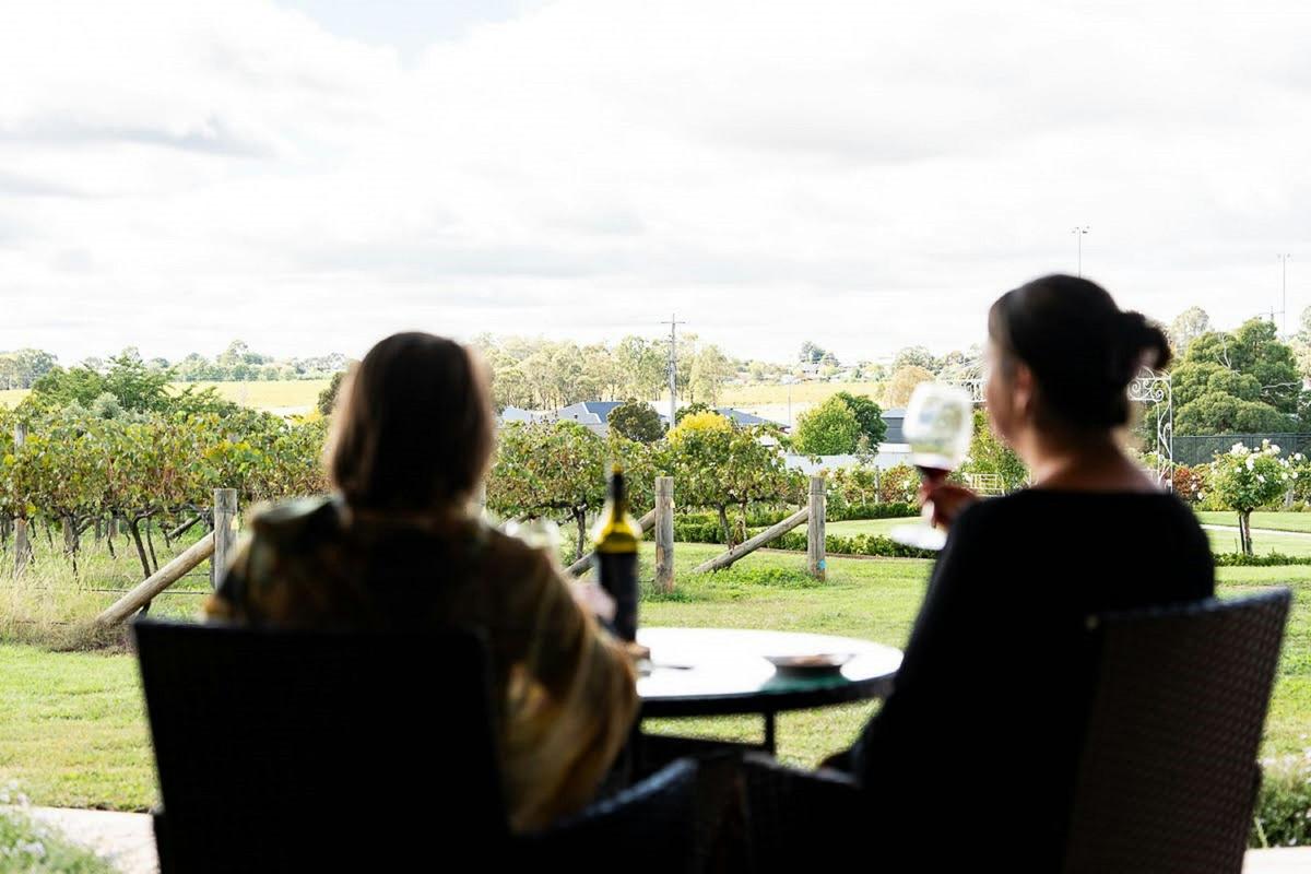 Ladies enjoying a glass of wine on balcony overlooking vines at aDe Bortoli Rutherglen Estate accomm