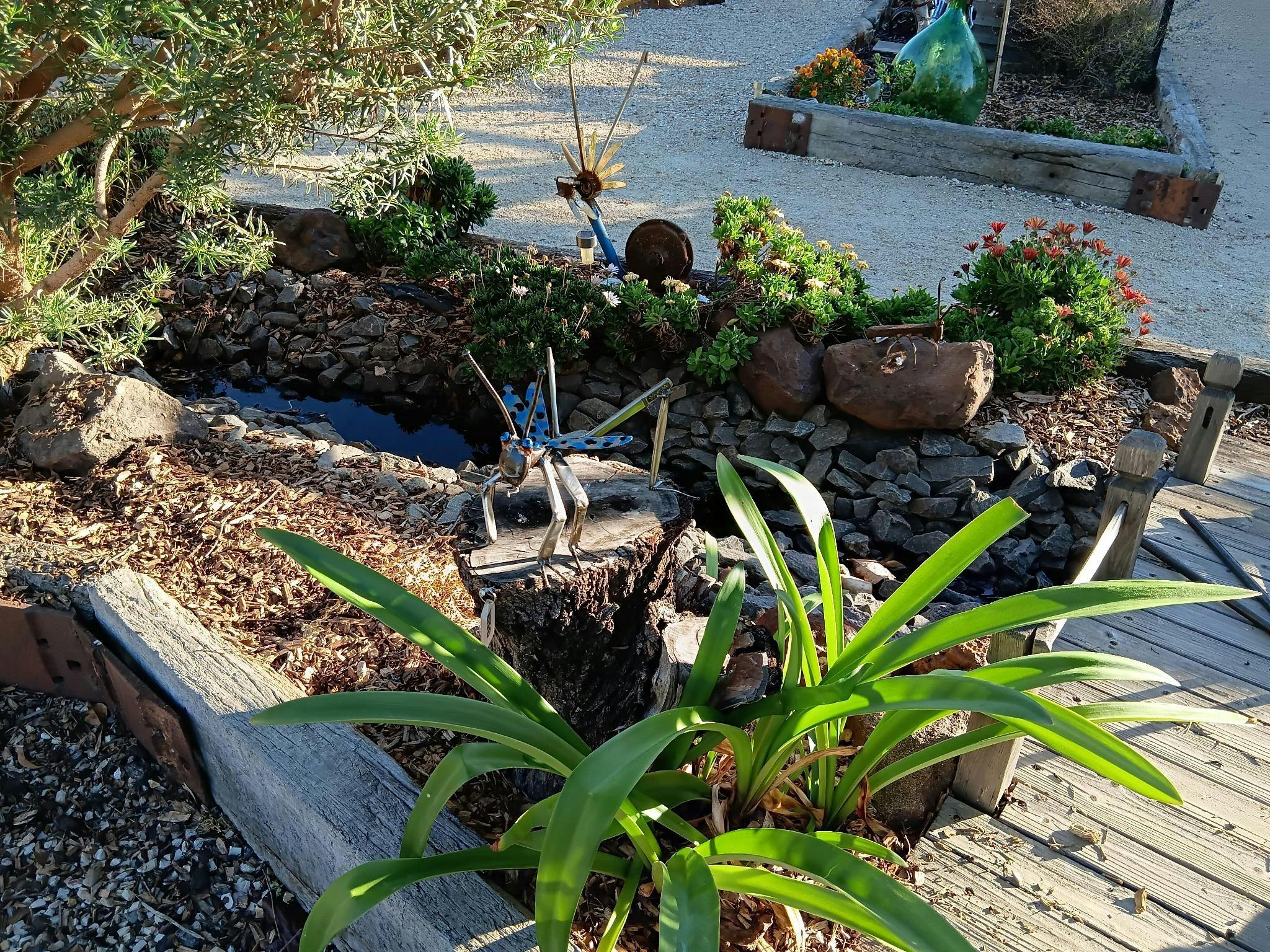 Close up of a sculpture grasshopper in a garden bed