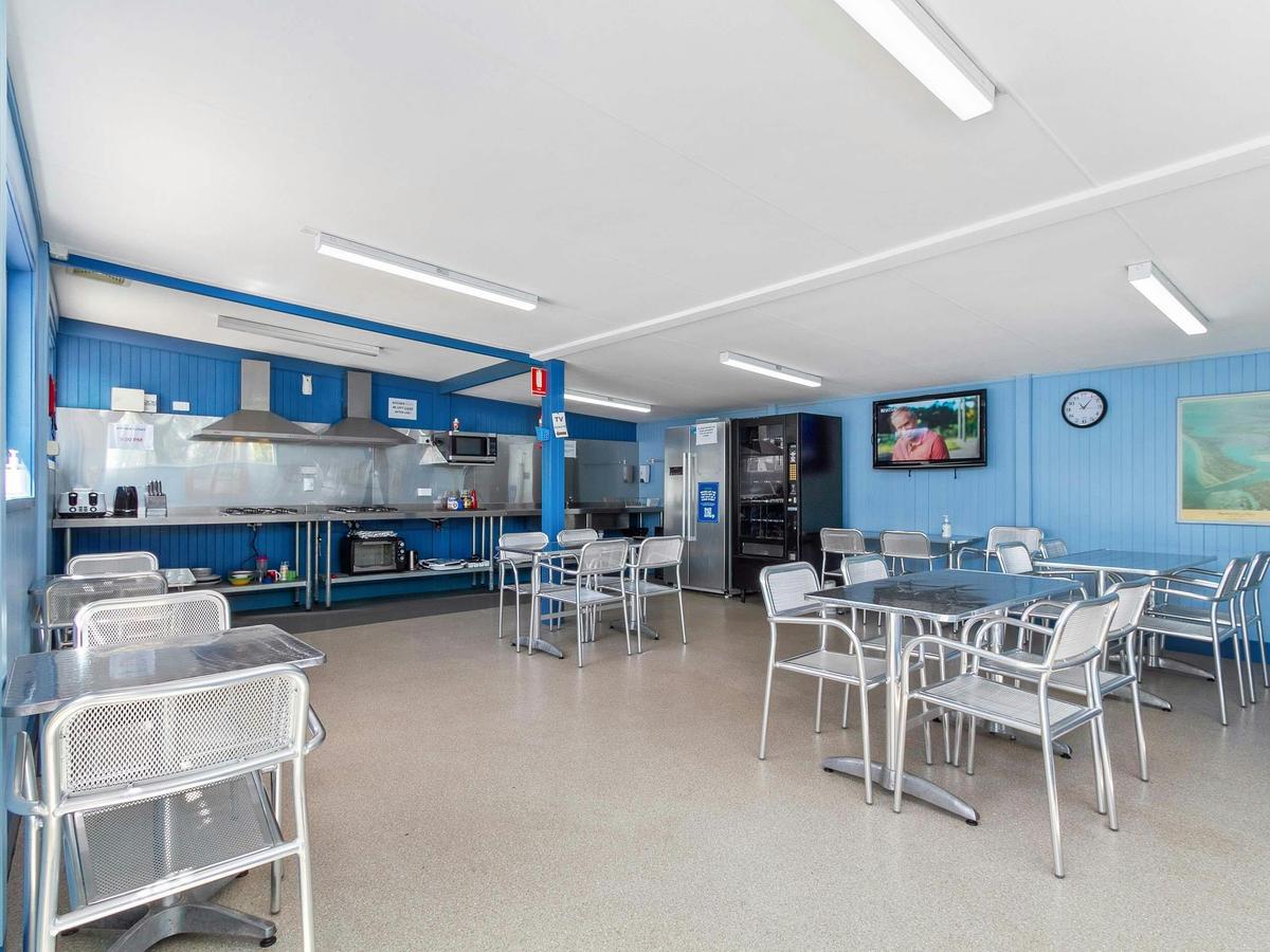 Neat camp kitchen, with plenty of tables & chairs, food prep areas, cook tops and fridges.