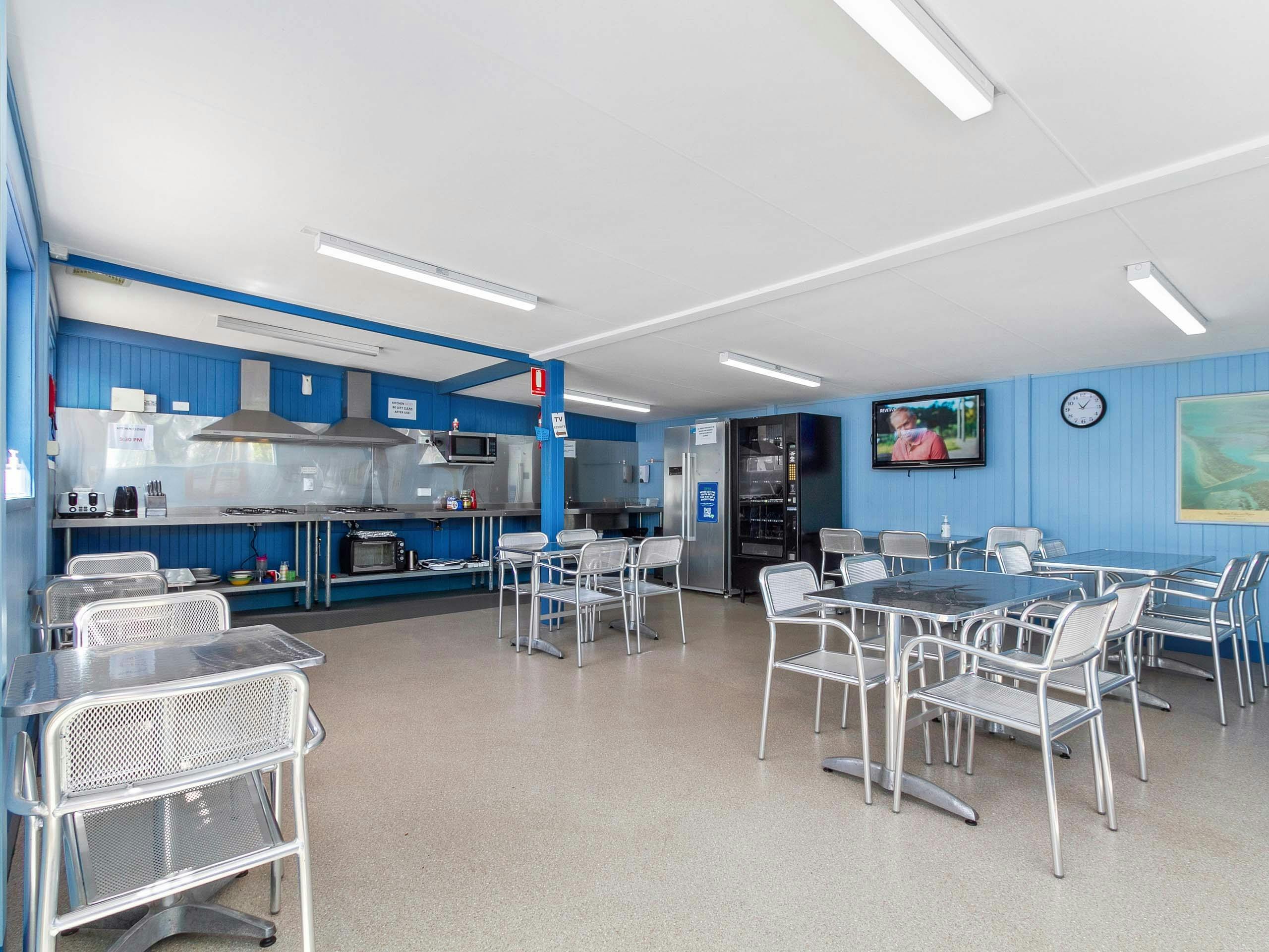 Neat camp kitchen, with plenty of tables & chairs, food prep areas, cook tops and fridges.