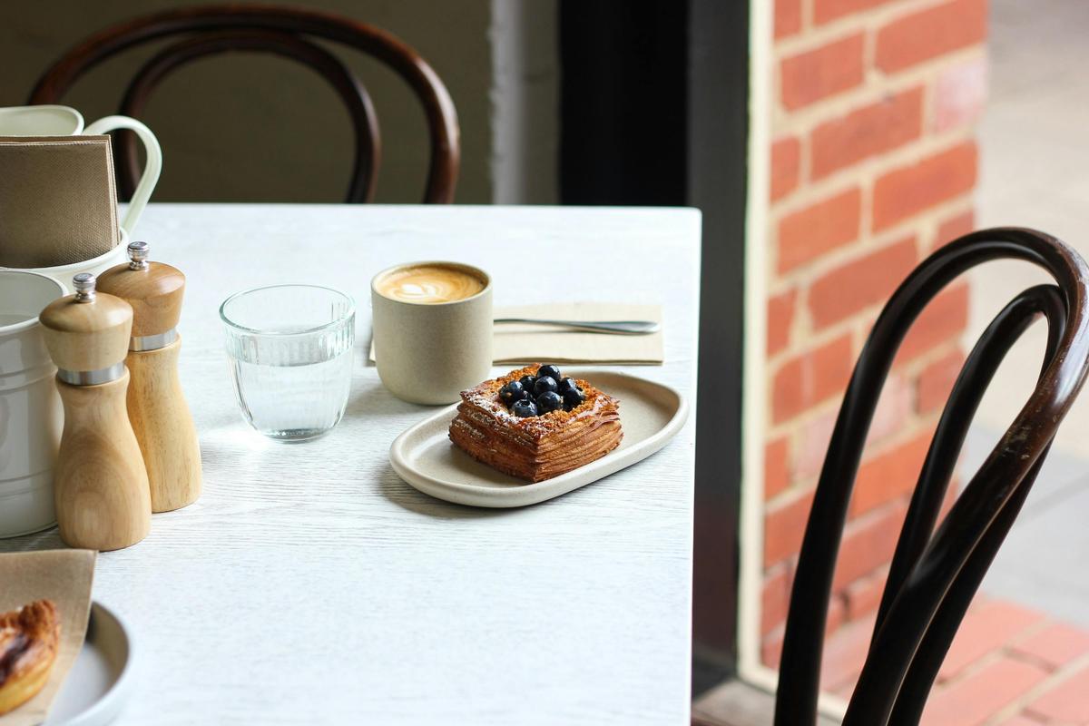 A danish pastry and a coffee on a table by the window
