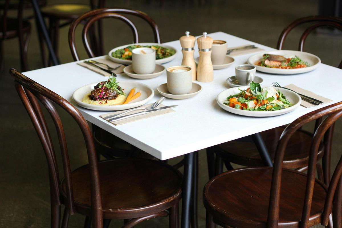 Four a la carte lunch dishes and a selection of coffees arranged on a four top dining table