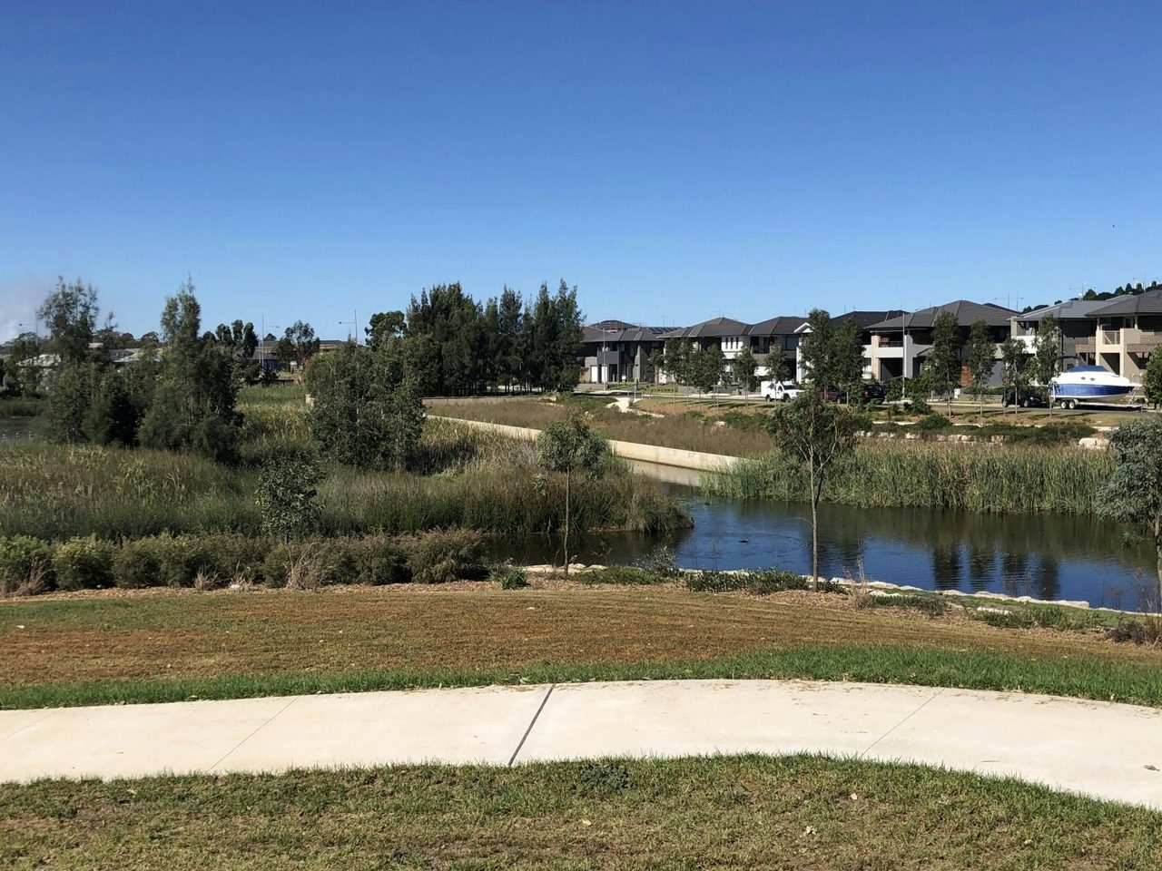 Pathway with Kolombo Reserve lake and houses in the background