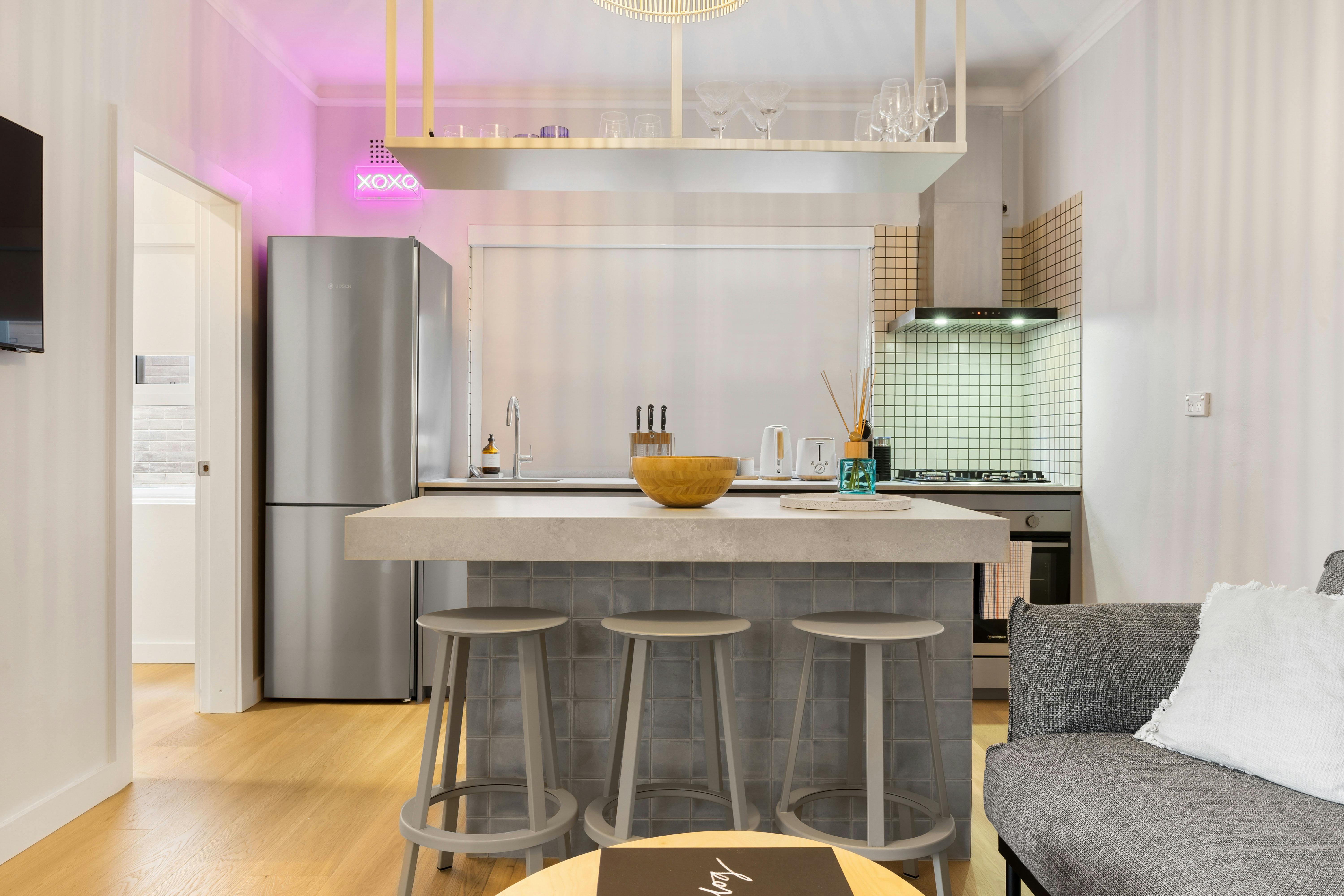 Modern kitchen with stylish finishes, a sleek bar area, and vibrant neon lighting.
