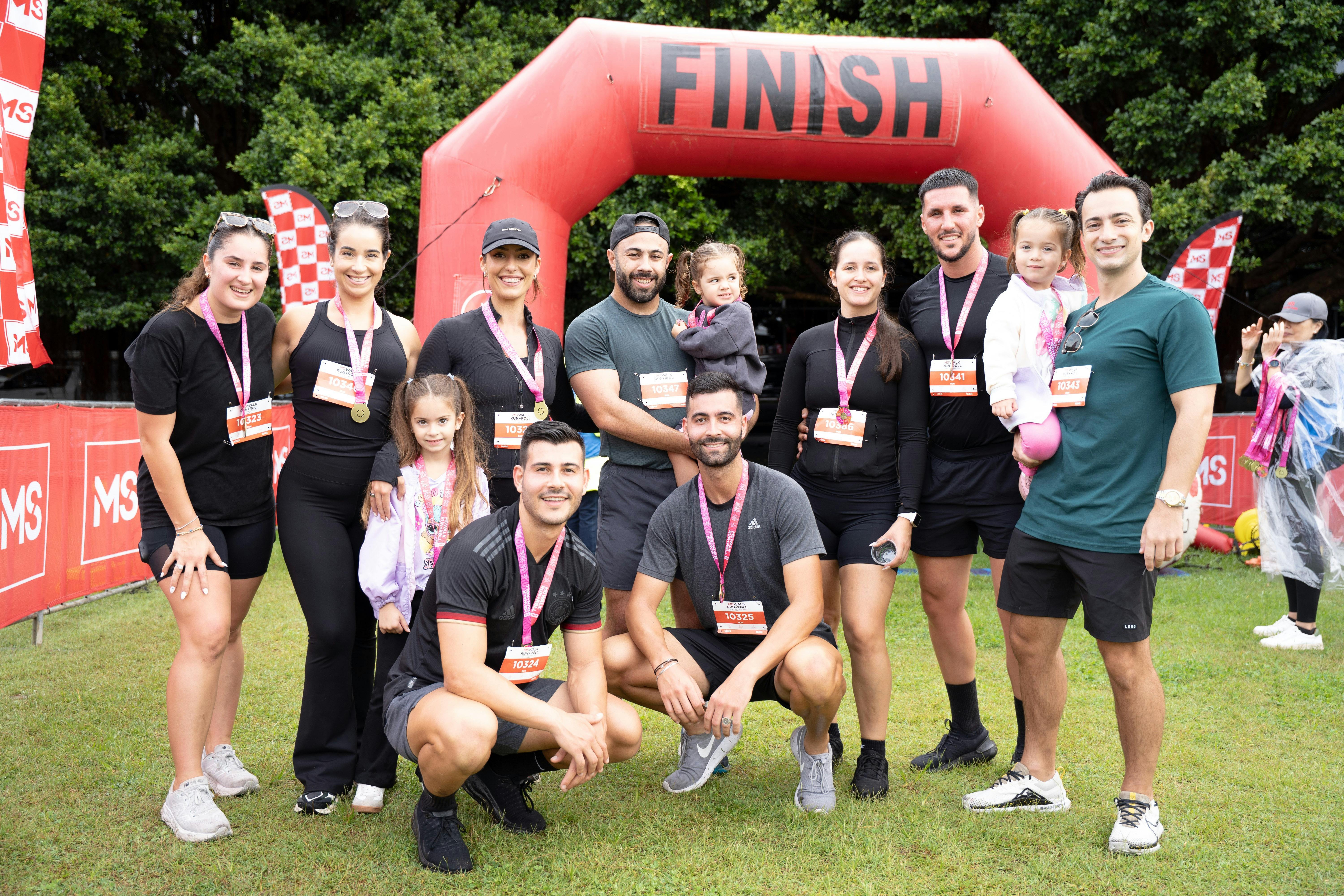 Group of people with participant medals standing in front of the finishing arch.