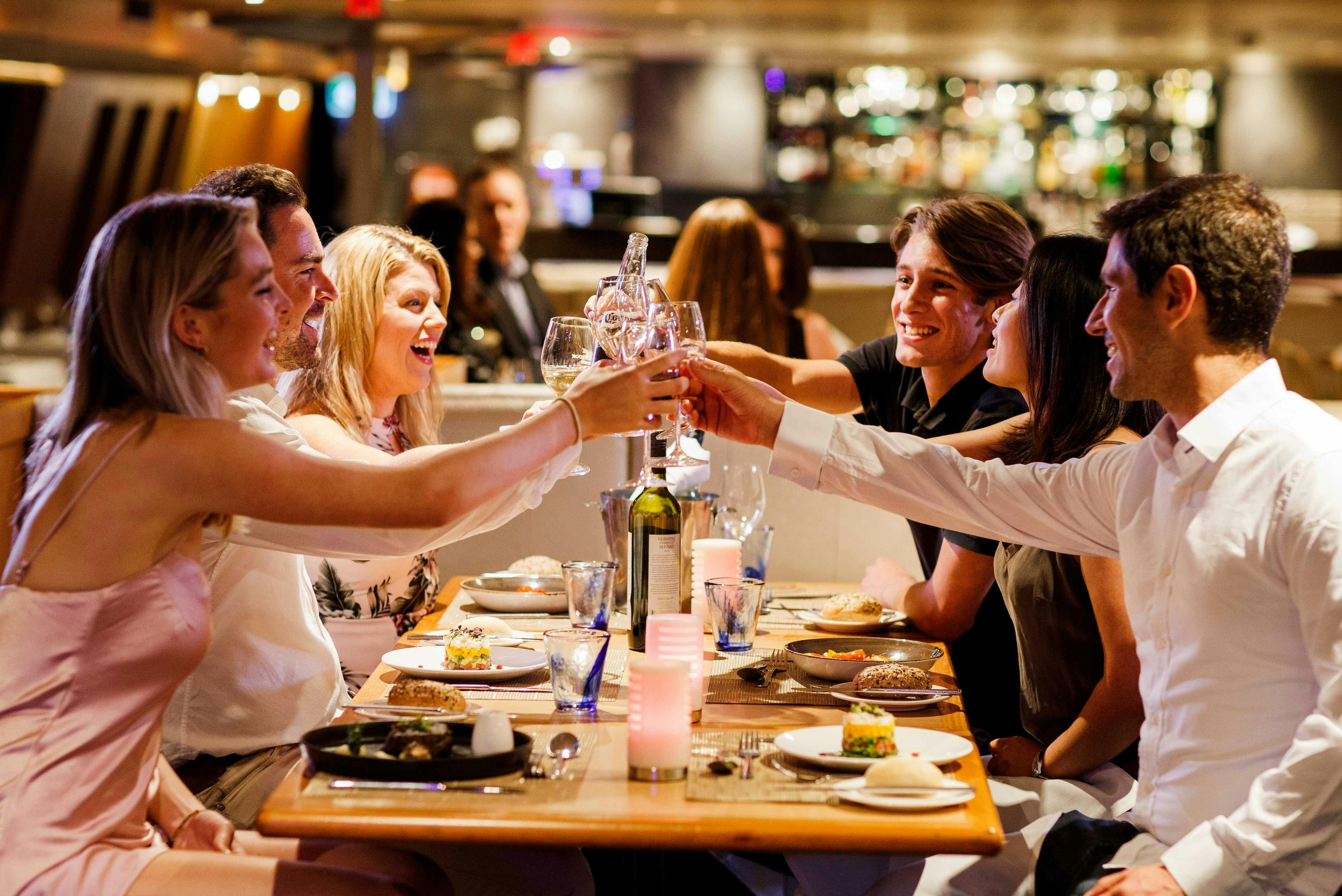 Dinner group of friends laughing and toasting wine glasses