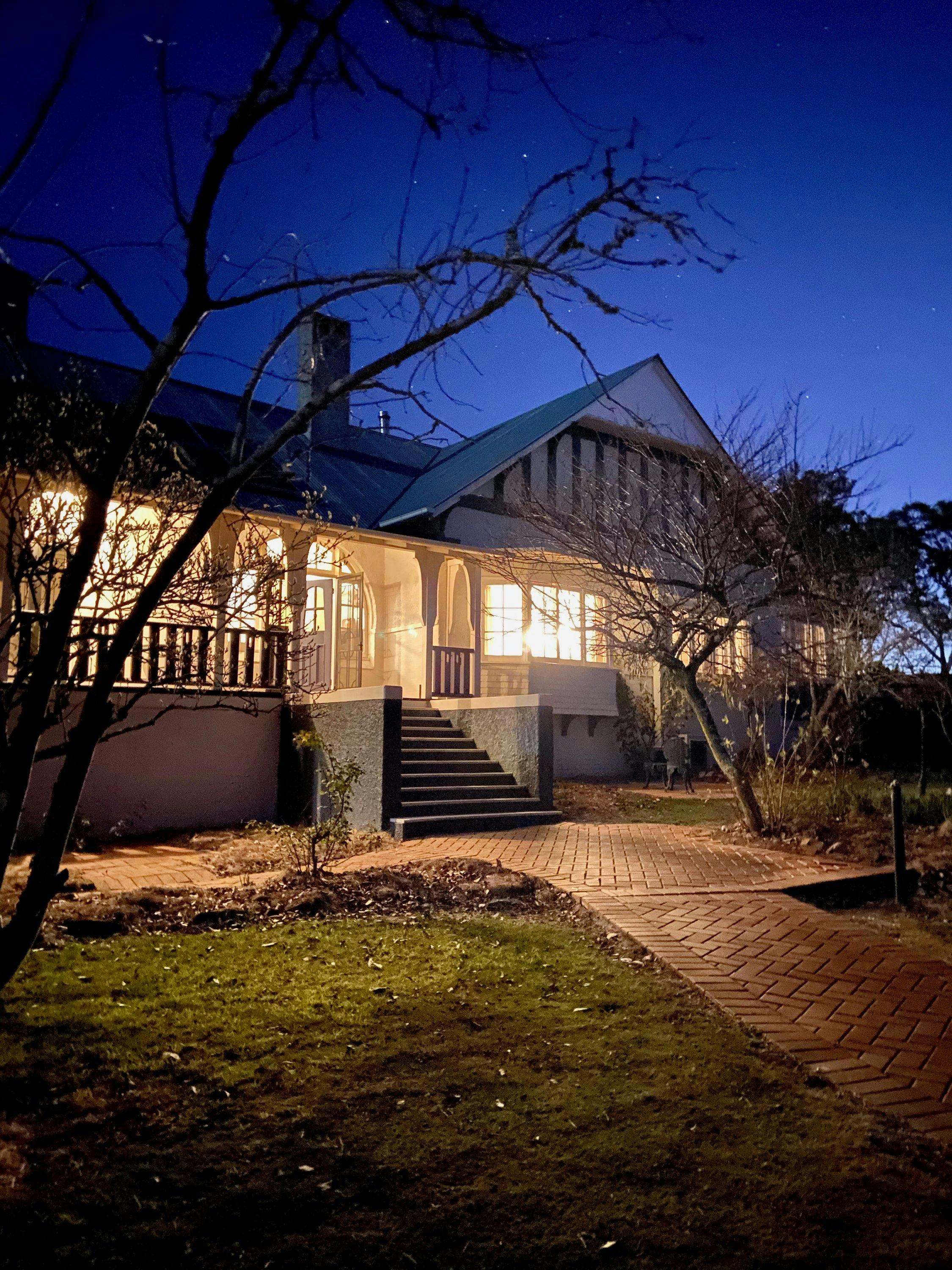 The beautiful homestead lit up at night time.