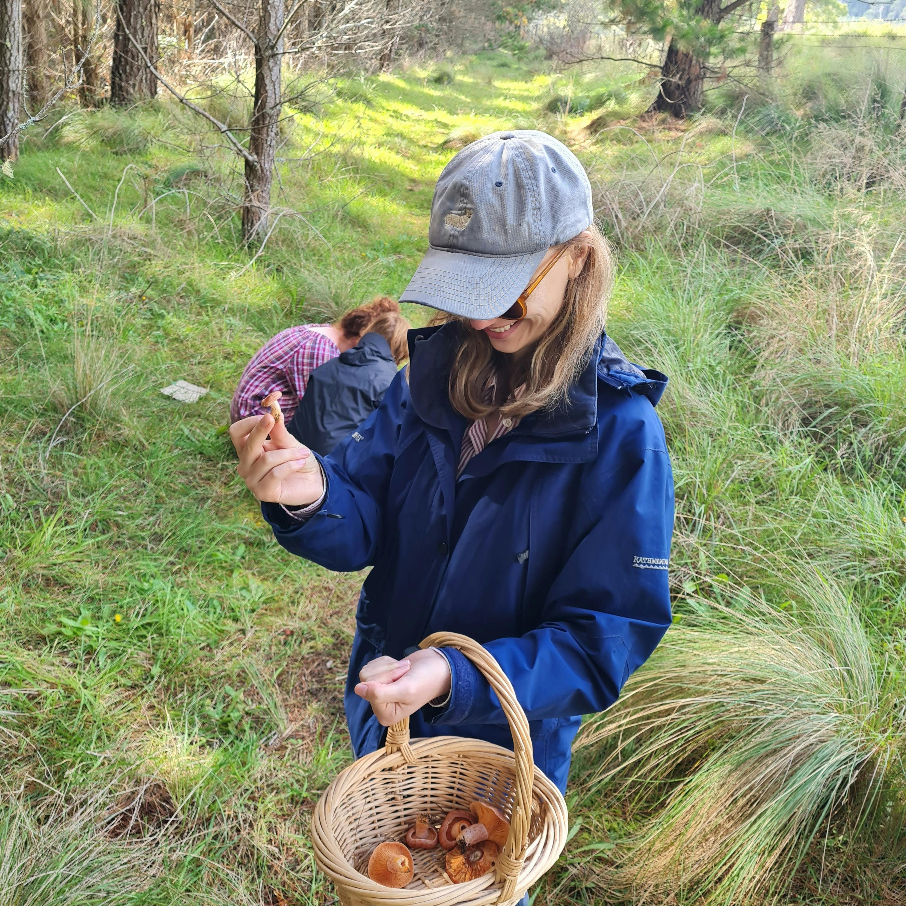 Mushroom forager with a basket, holding a mushroom