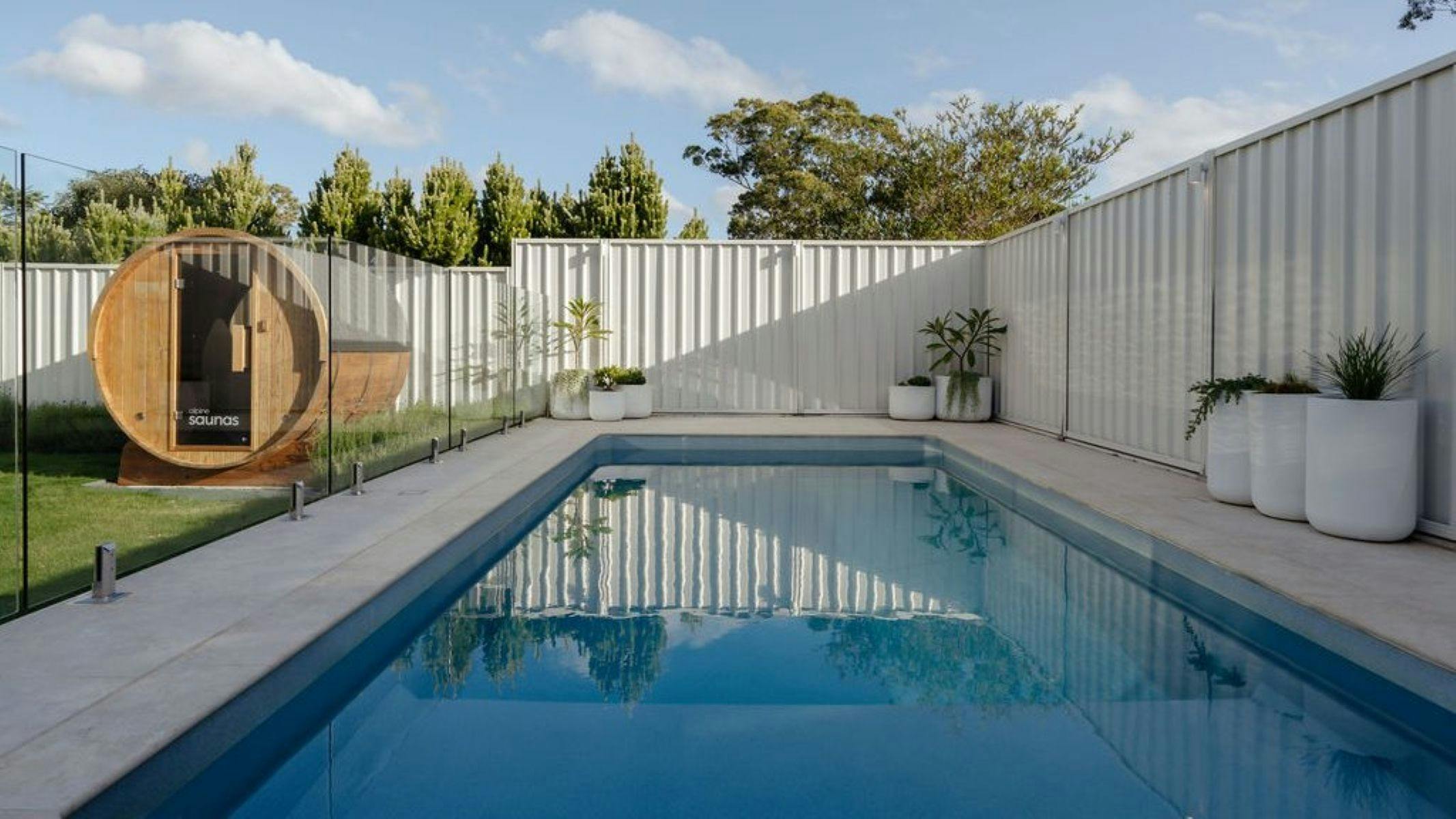 Dining and lounge flow effortlessly toward the garden, heated swimming pool and private sauna beyond