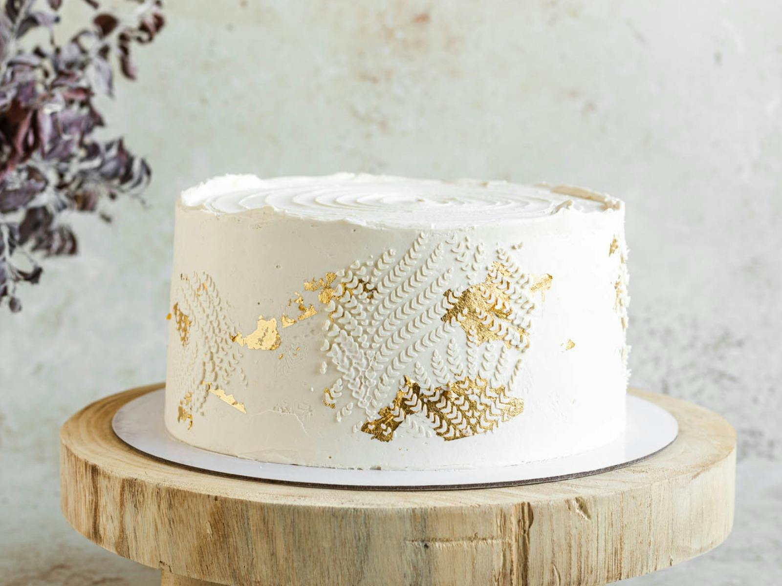 buttercream cake with golden textured buttercream on a wooden cake stand