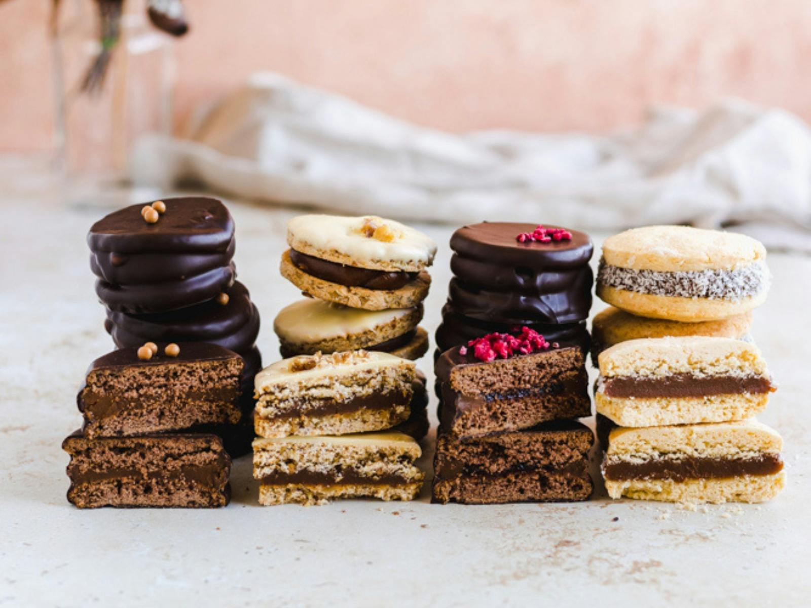 four types of alfajores, on a beige backdrop