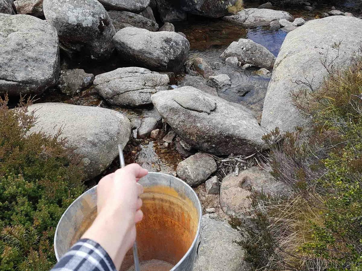 Water is life - fetching a pale of water from a stream nearby a hut. Many huts are near streams.