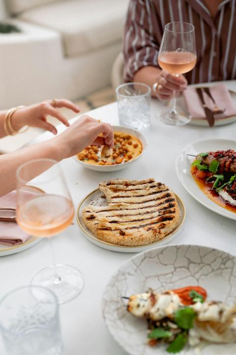 Three plates of food and a wine glass