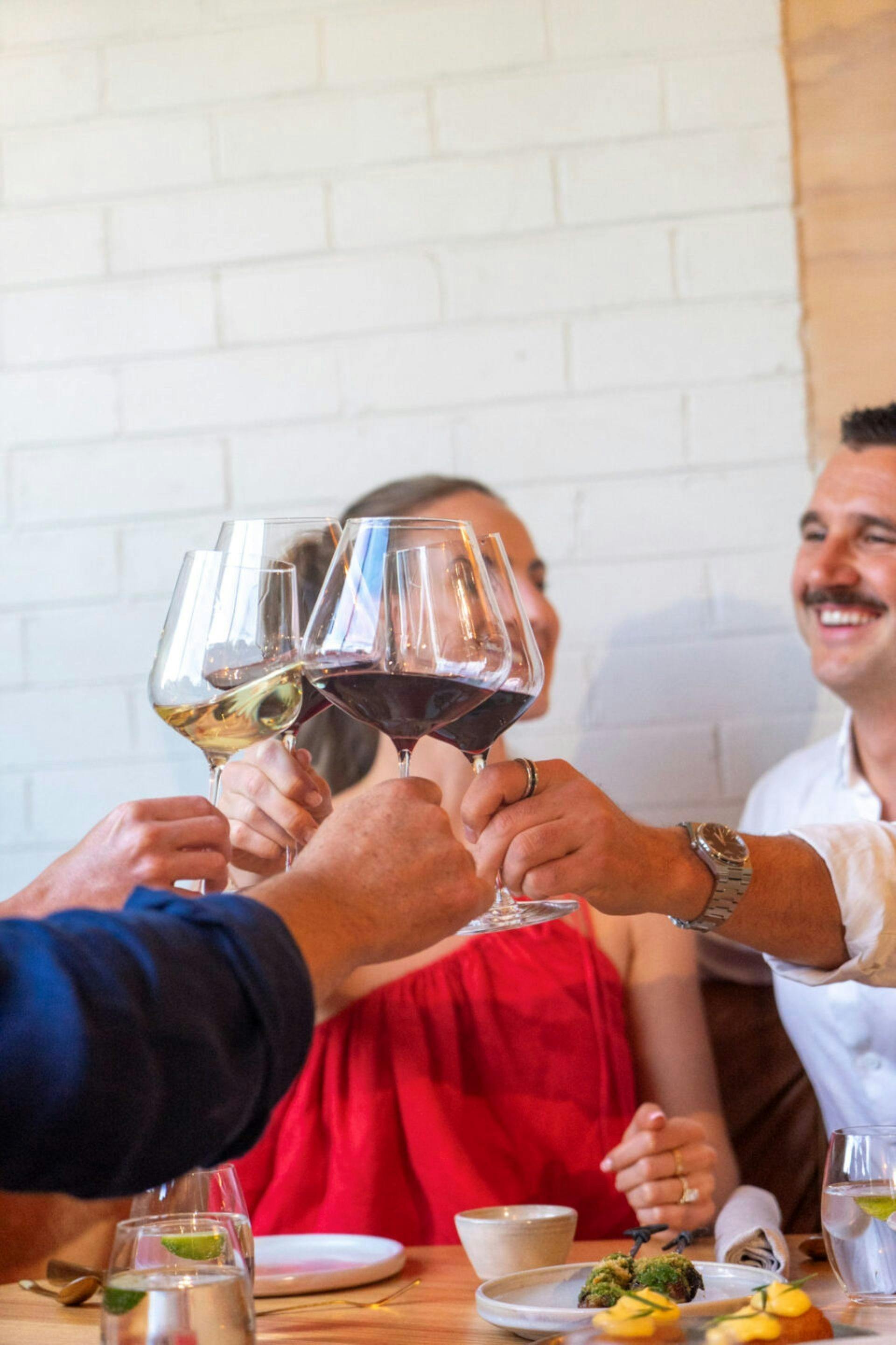 Four people clinking wine glasses in a celebratory toast