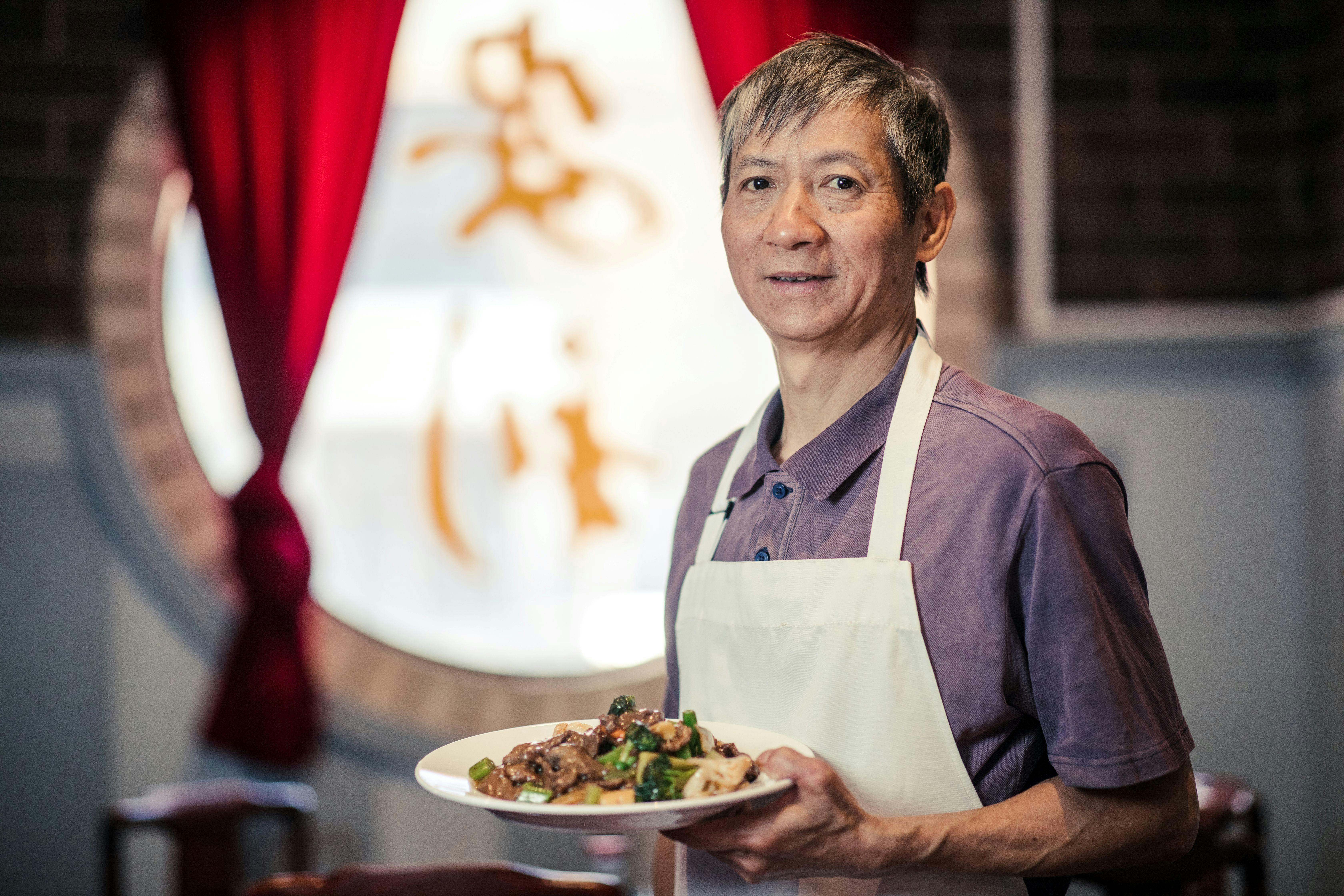 Staff member holding beef dish in front of window