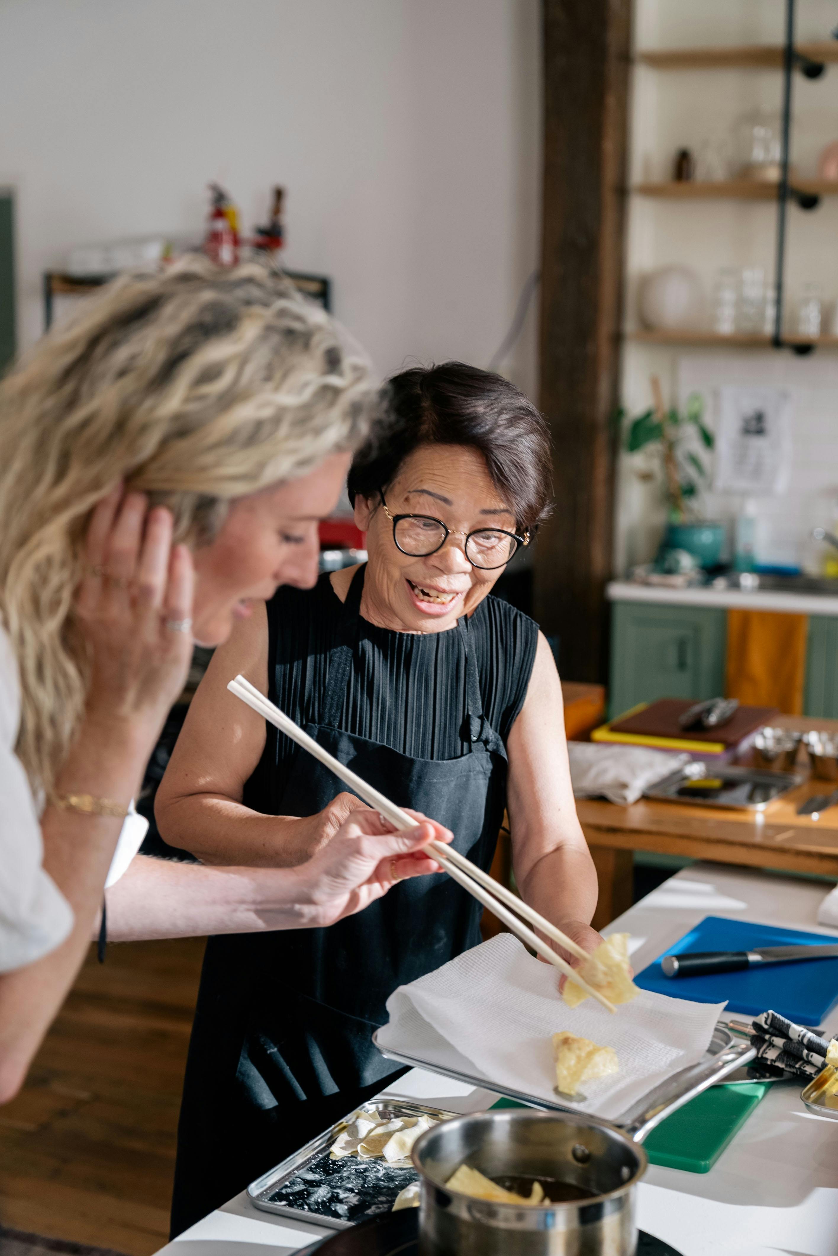 Mum guiding a guest on frying dumplings