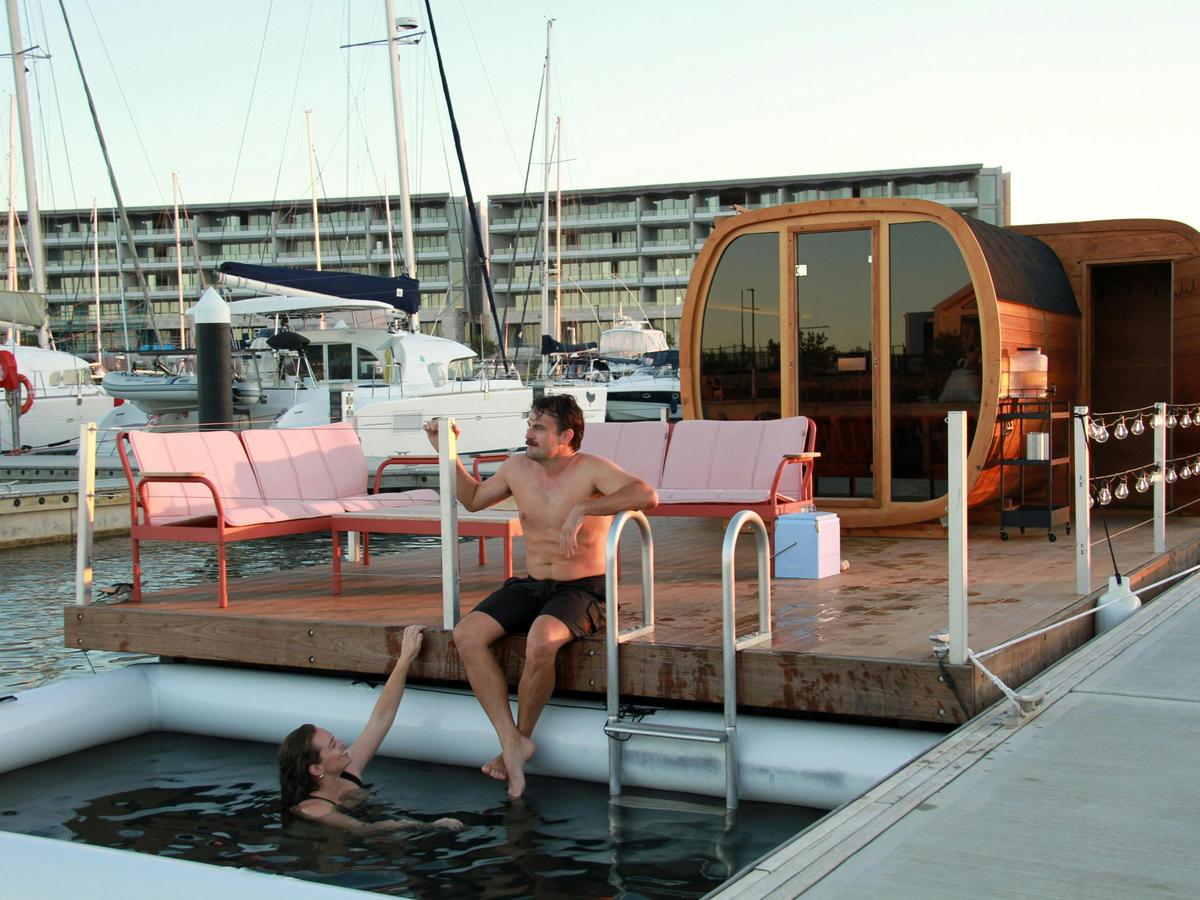 View of the floating sauna in the evening  with people sitting on the pontoon