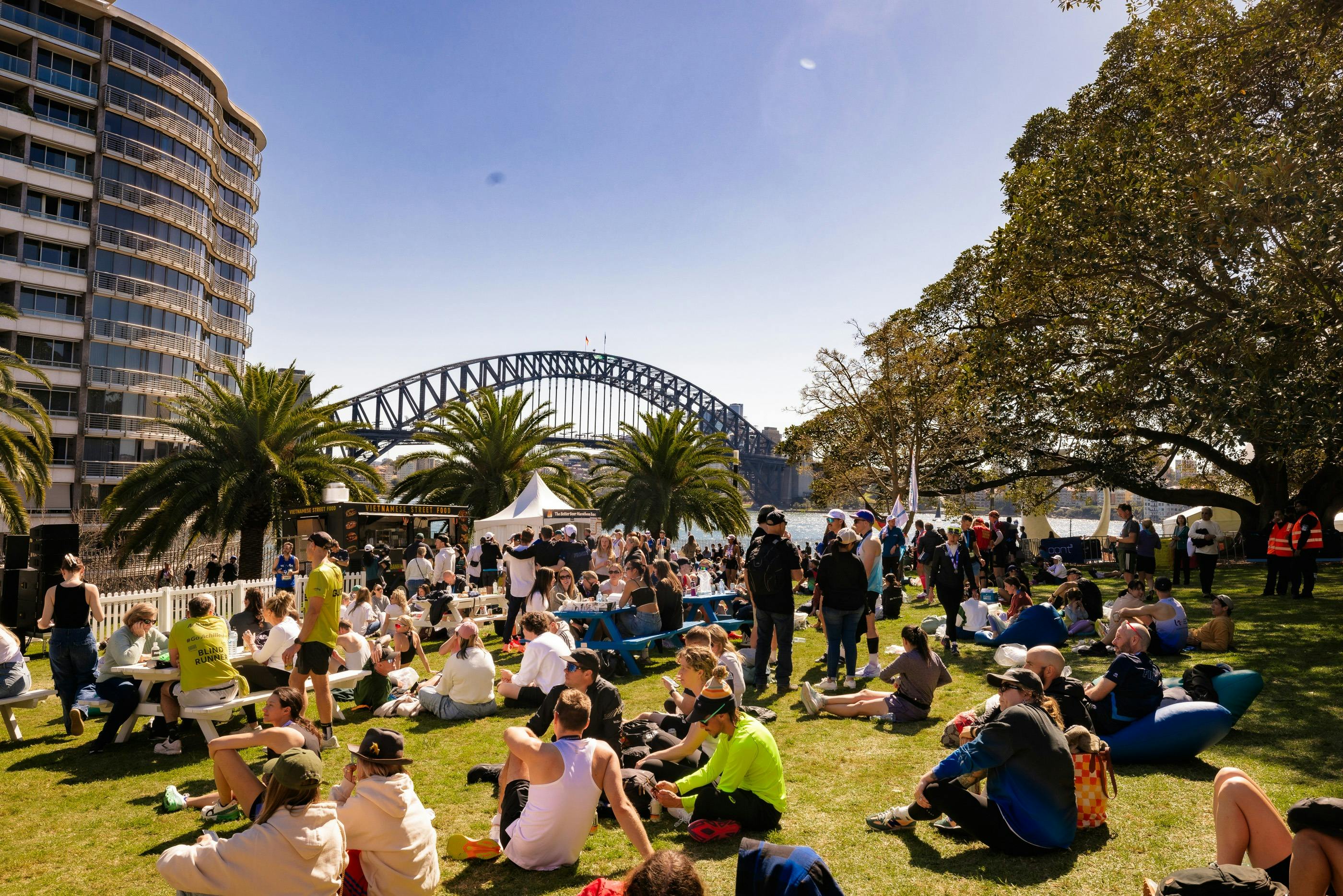 Tarpeian Lawn filled with visitors sitting, eating, drinking and enjoying the sun and harbour views
