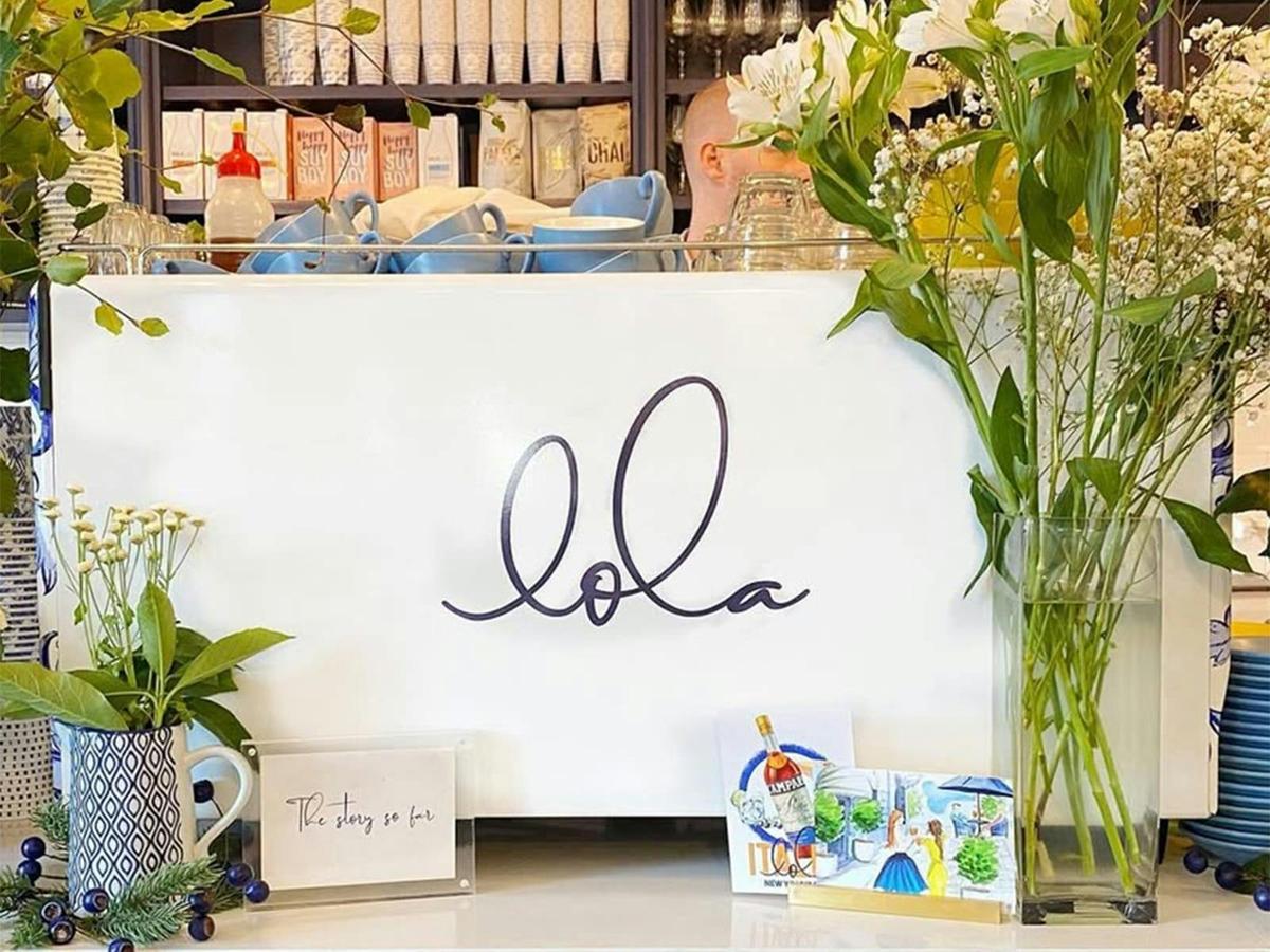 Decorative café display at Lola featuring elegant cursive branding, fresh flowers,